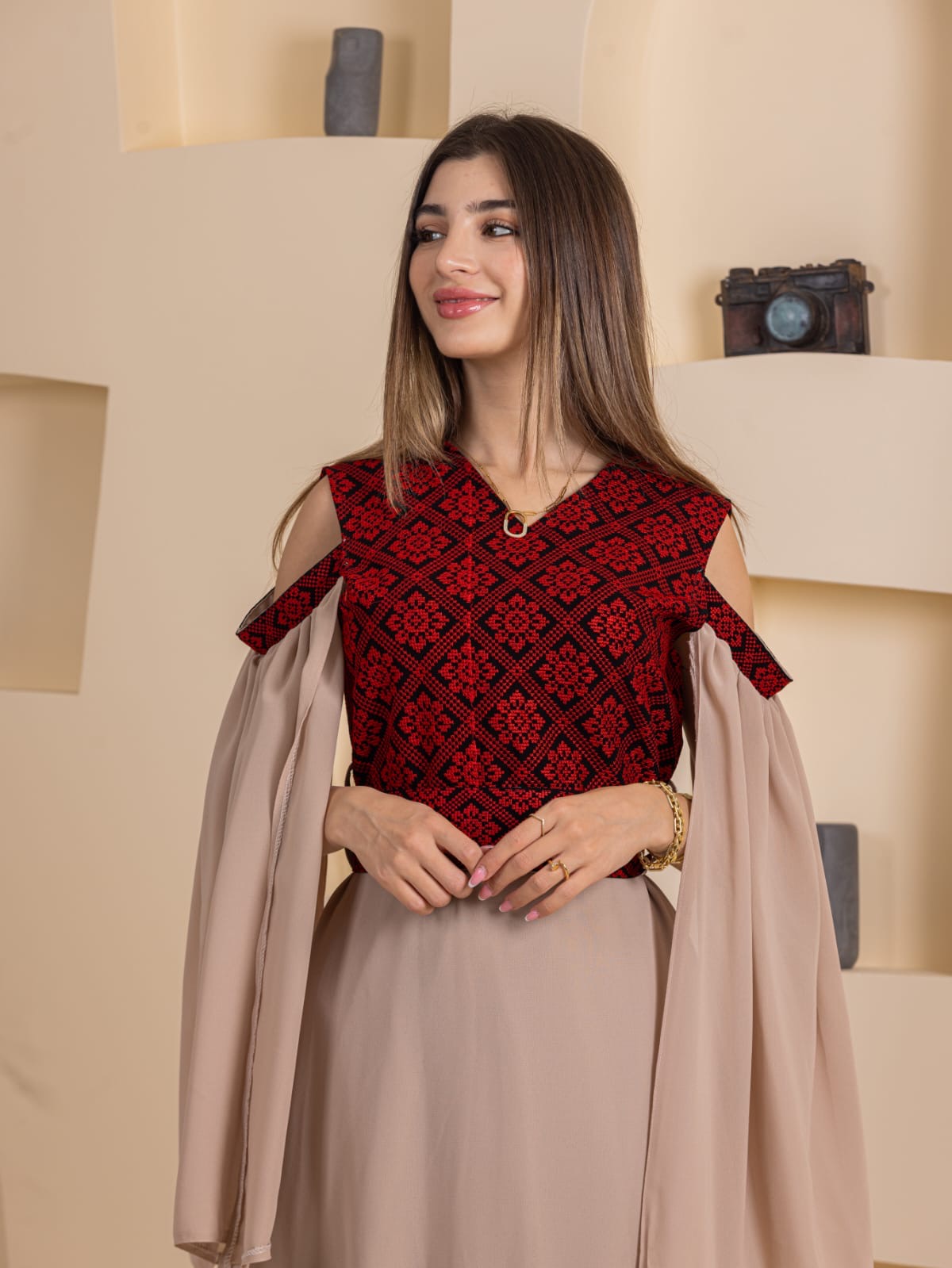 Model wearing Palestinian Essence Dress with red embroidered bodice and beige flowing cape sleeves and skirt