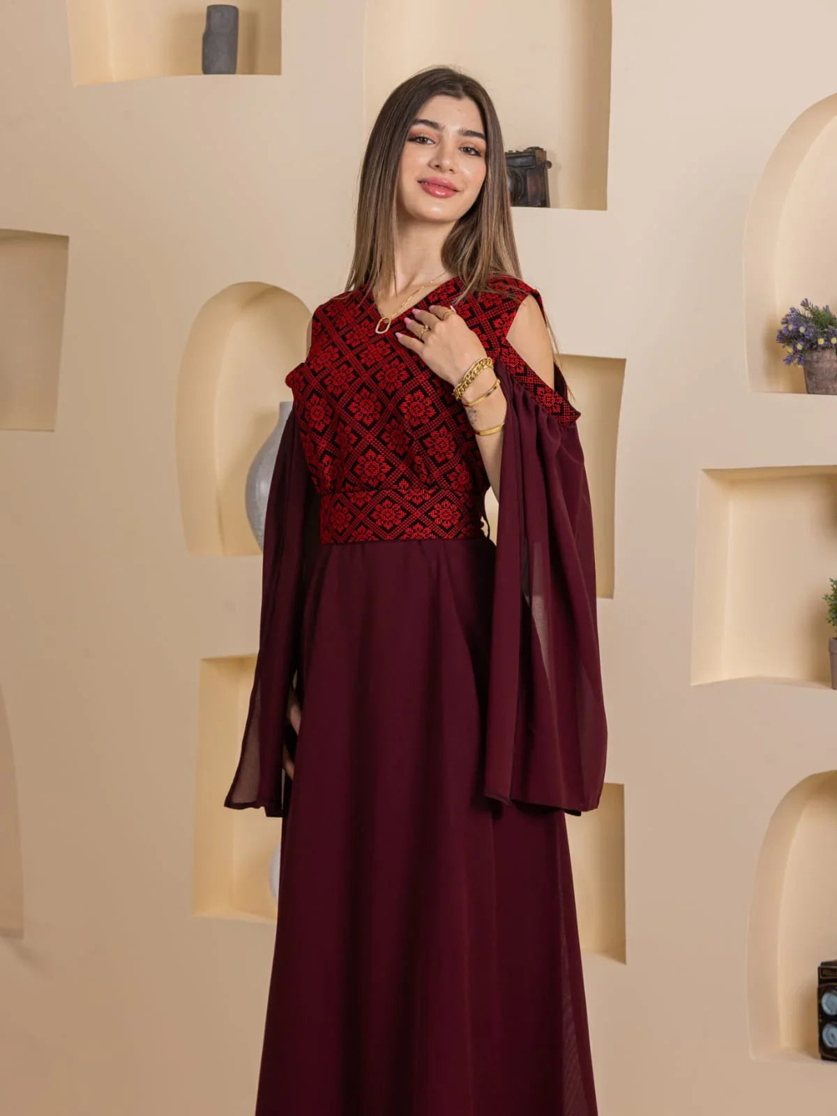 Model wearing Palestinian Essence Dress by Palestinian Elegance deep burgundy embroidered bodice cold shoulder chiffon skirt