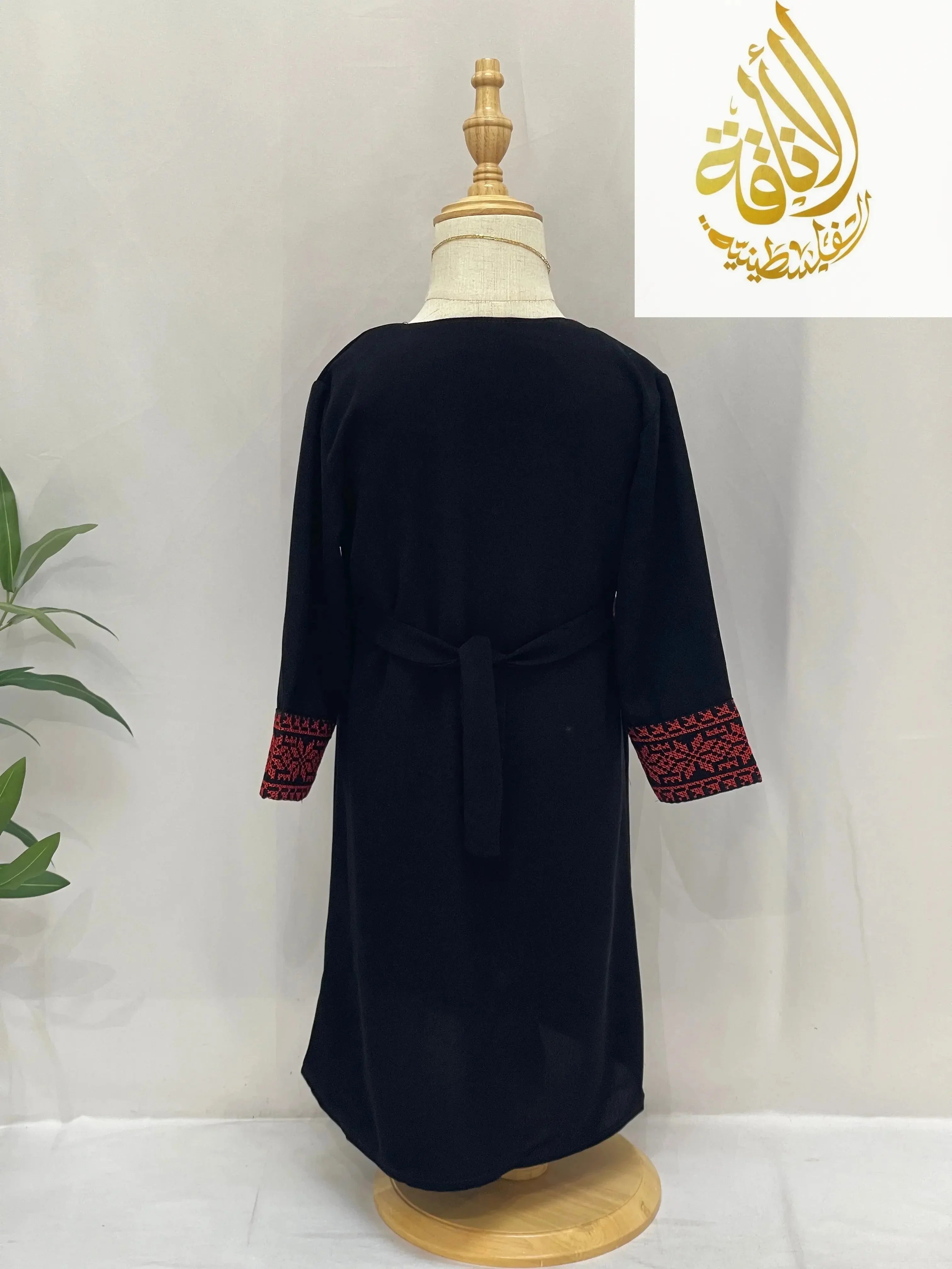 Back view of Kid's Haya Embroidered Abaya by Palestinian Elegance with red embroidered cuffs on black fabric
