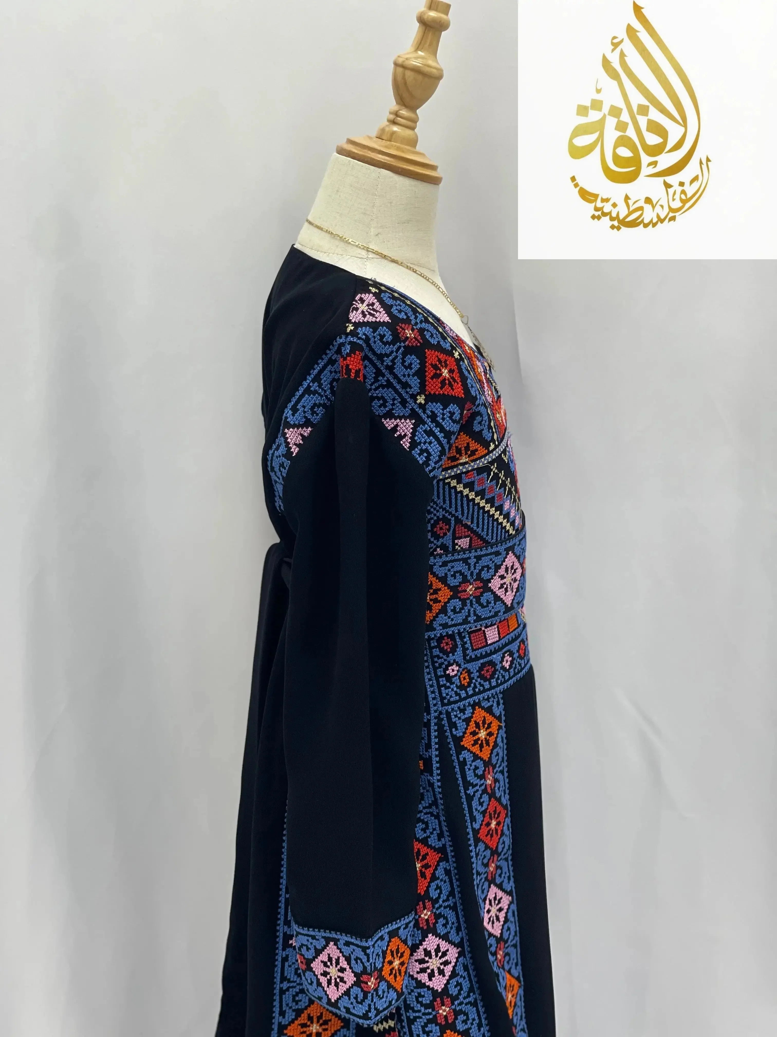 Palestinian Elegance embroidered thoub for girls in black with colorful geometric embroidery on a mannequin