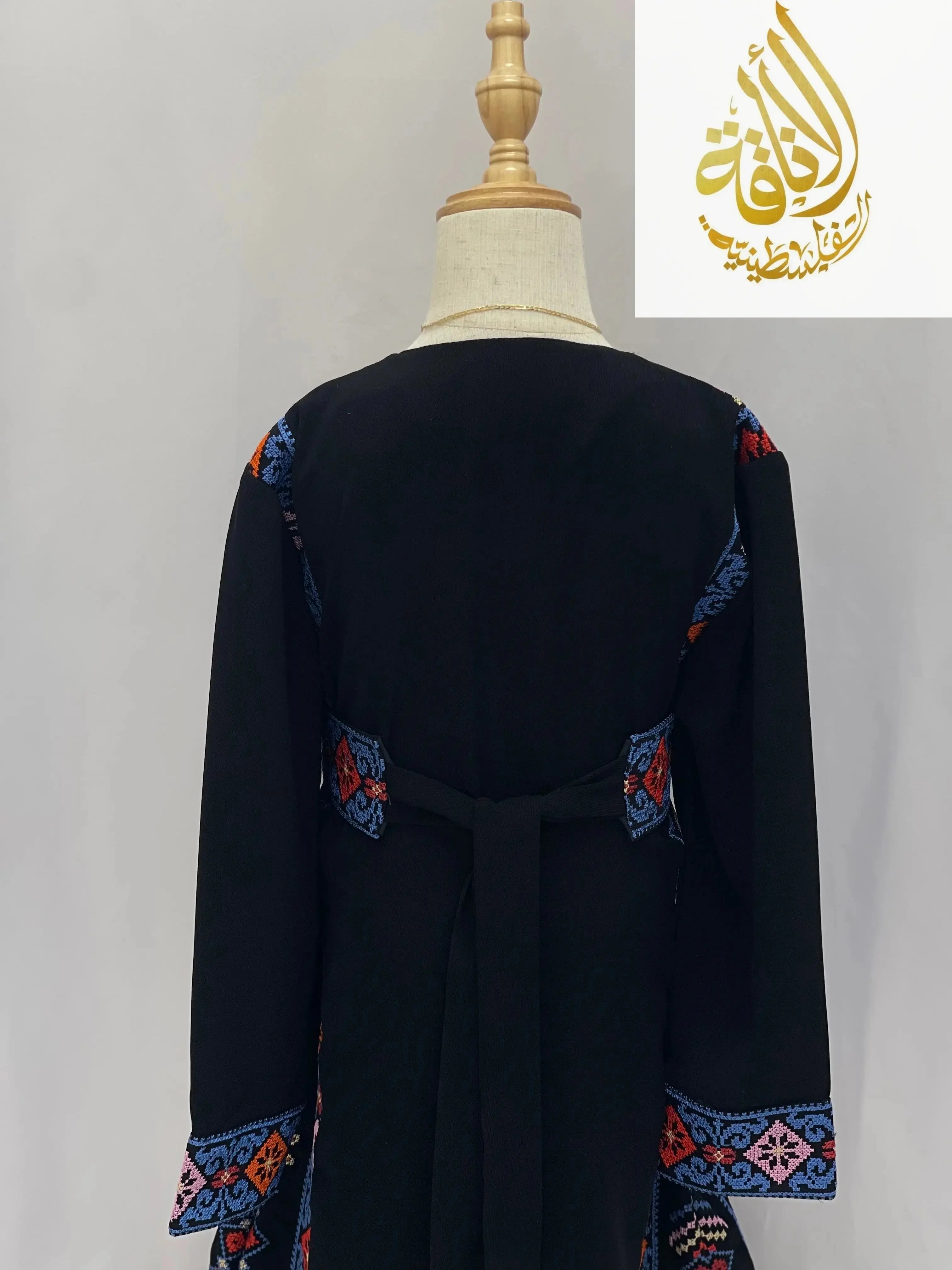 Back view of embroidered thoub for girls by Palestinian Elegance with colorful detailed embroidery on black fabric