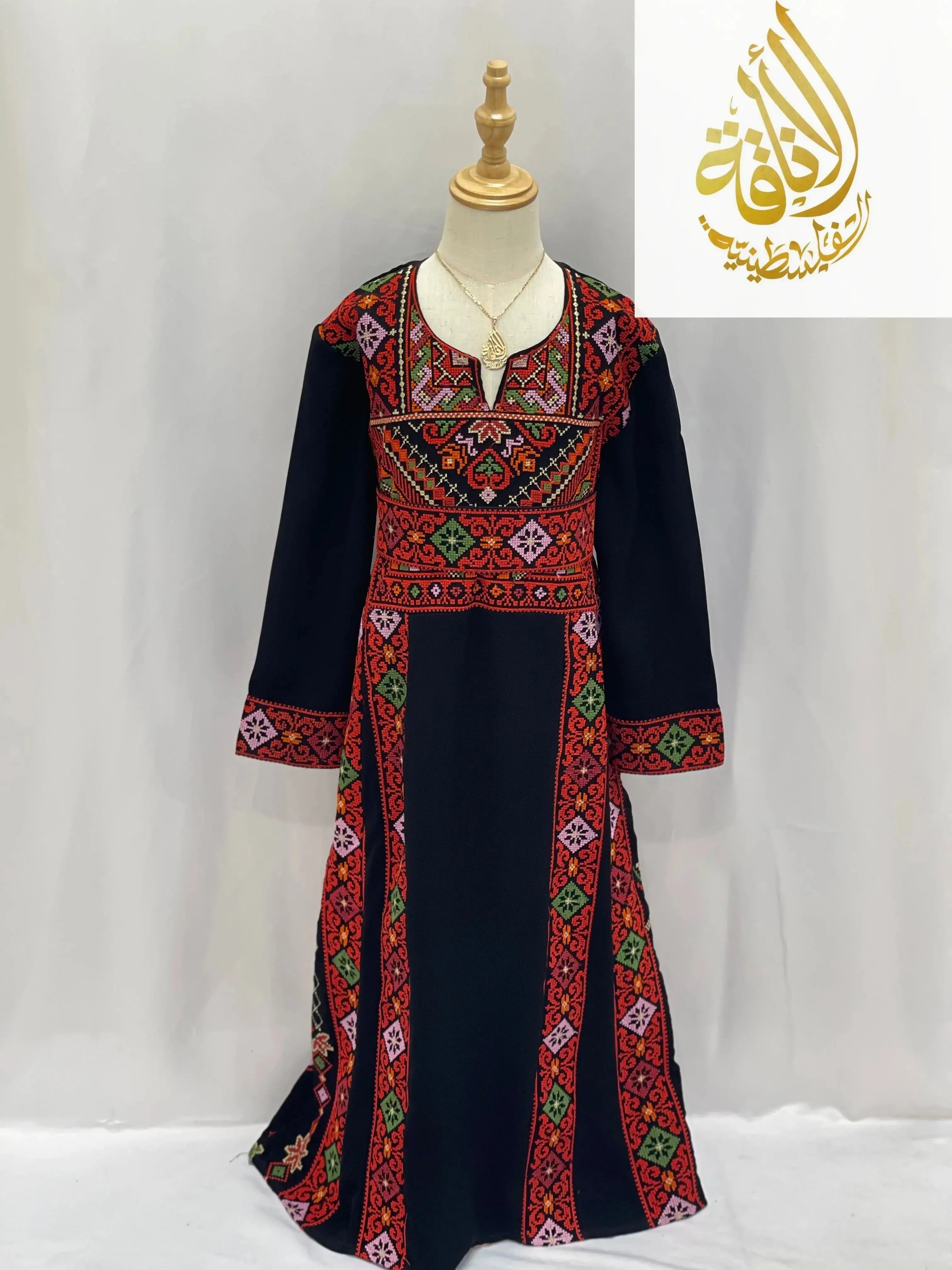 Embroidered thoub for girls by Palestinian Elegance with vibrant red green and purple traditional patterns on black fabric