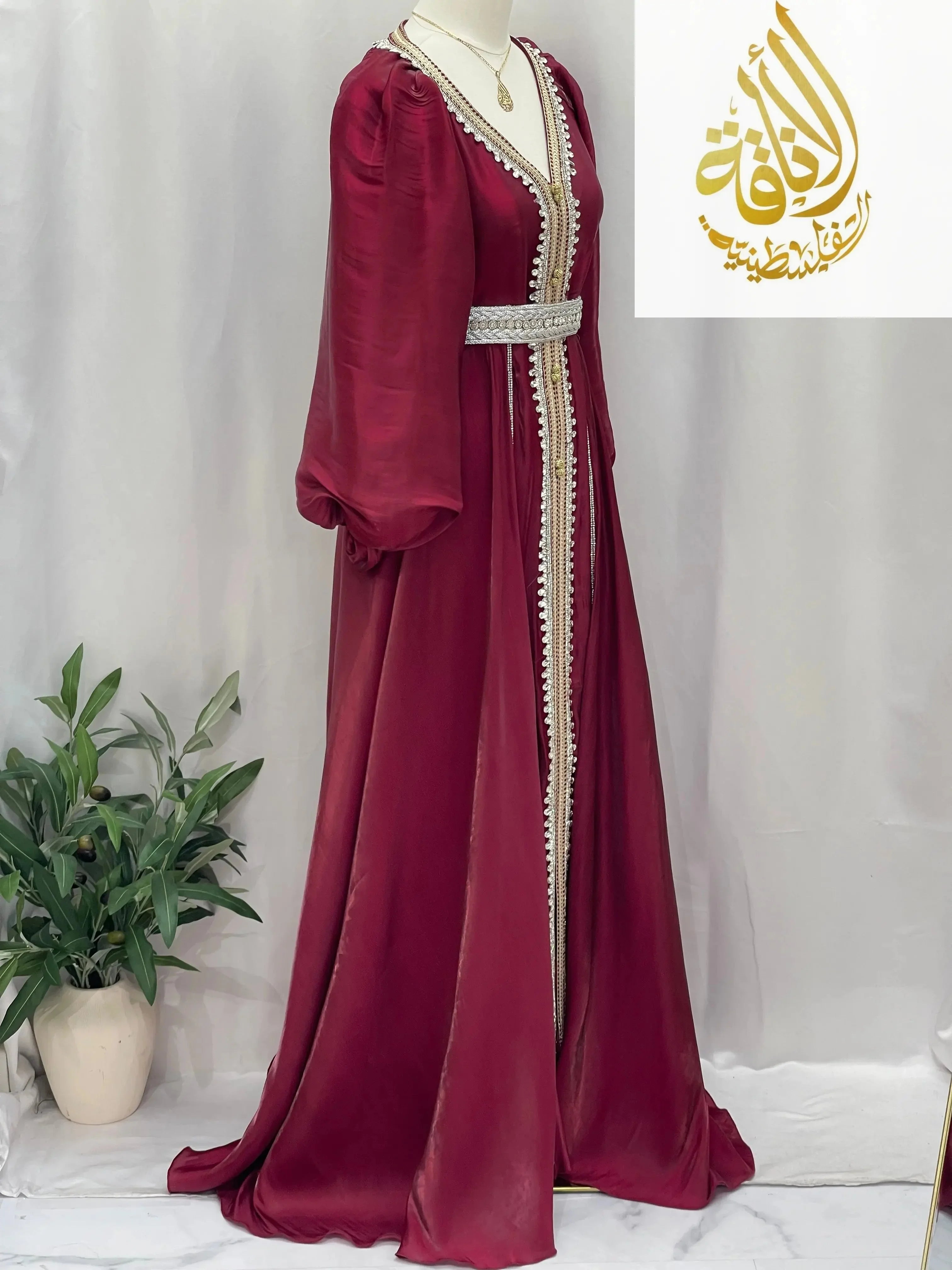 Palestinian Elegance burgundy puffy sleeves kaftan dress with white trim and decorative belt on mannequin