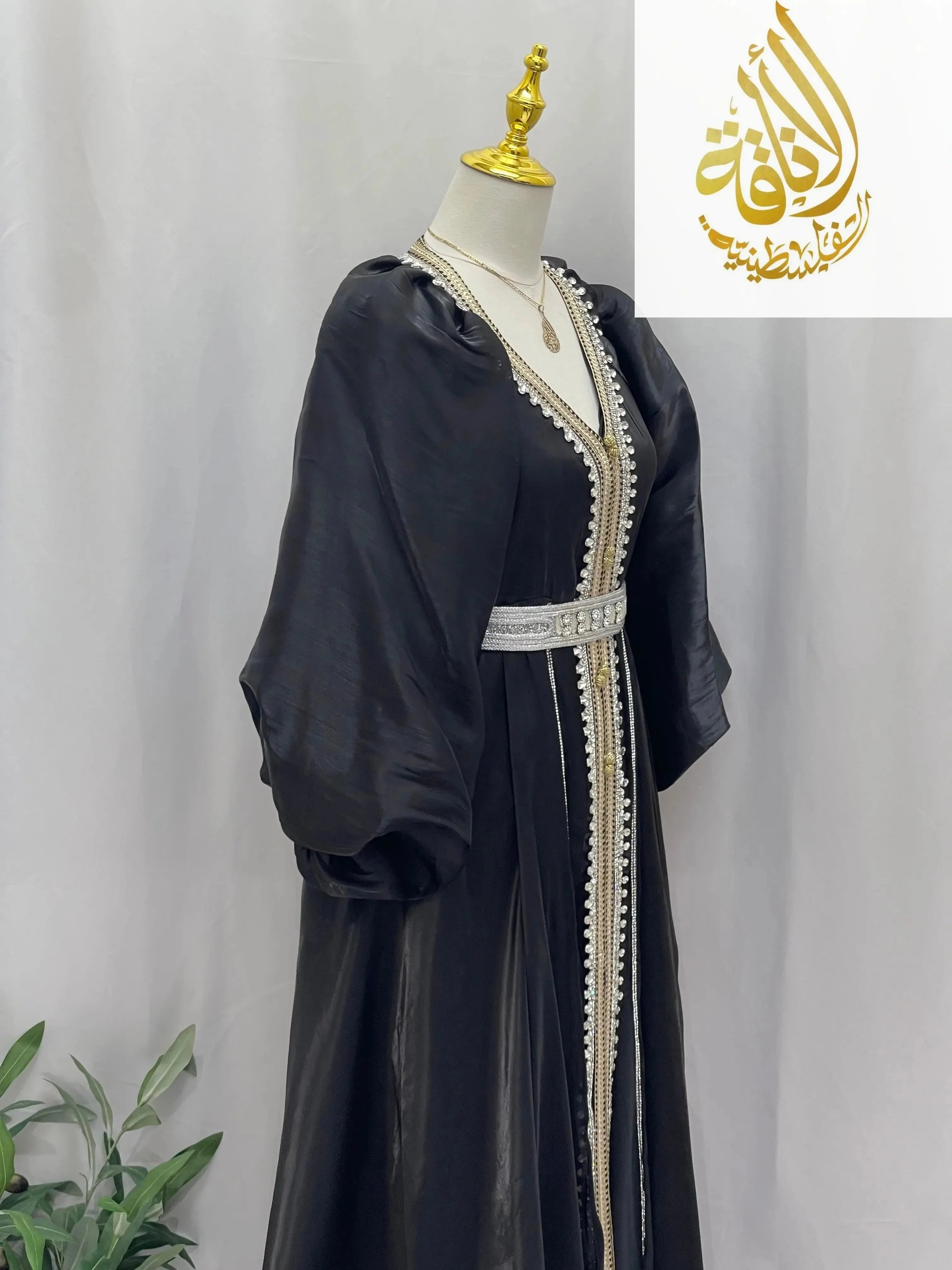 Palestinian Elegance black puffy sleeves kaftan dress with white decorative trim and belt on mannequin