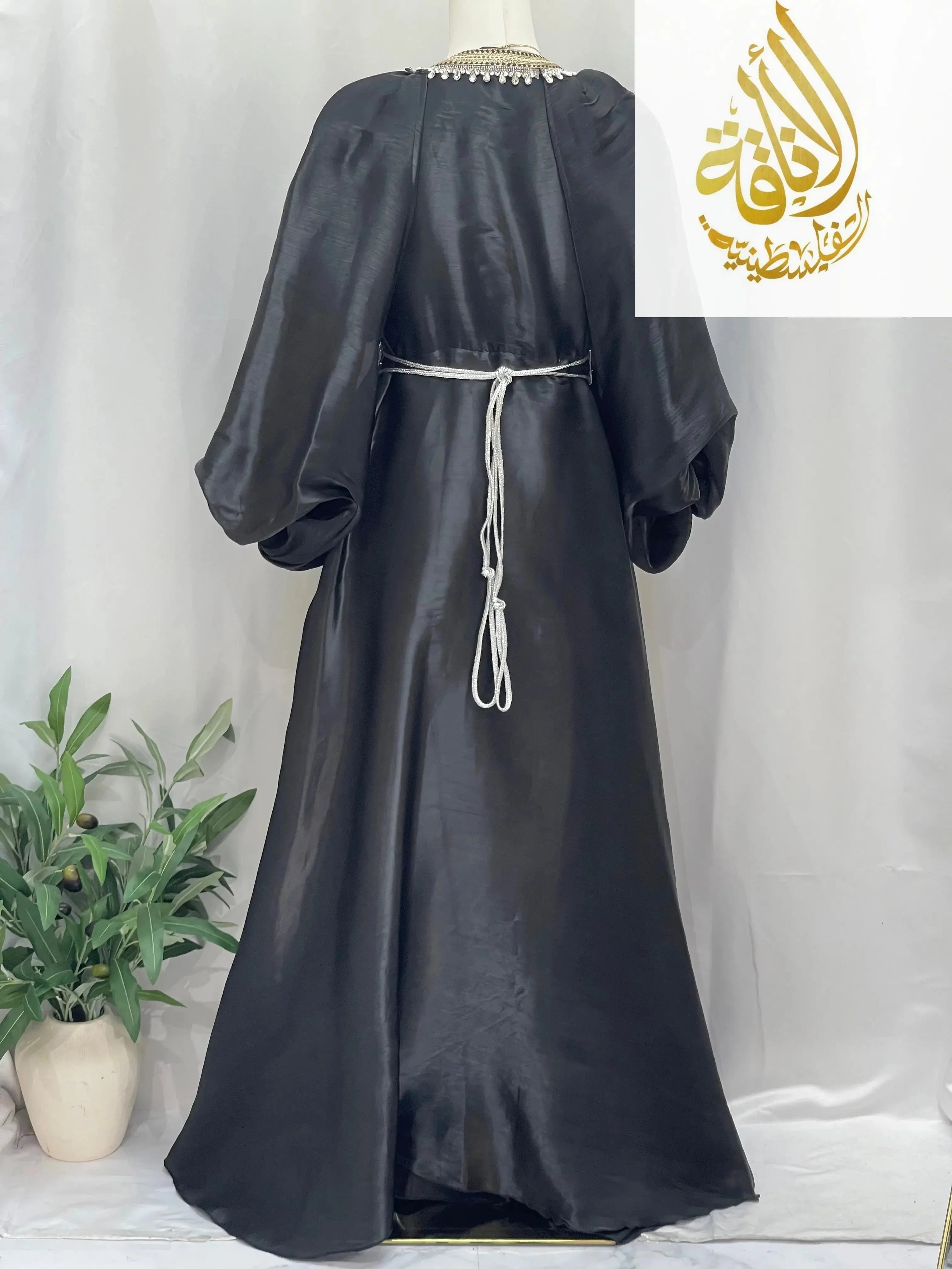 Palestinian Elegance black puffy sleeves kaftan dress with a tie waist belt on a mannequin