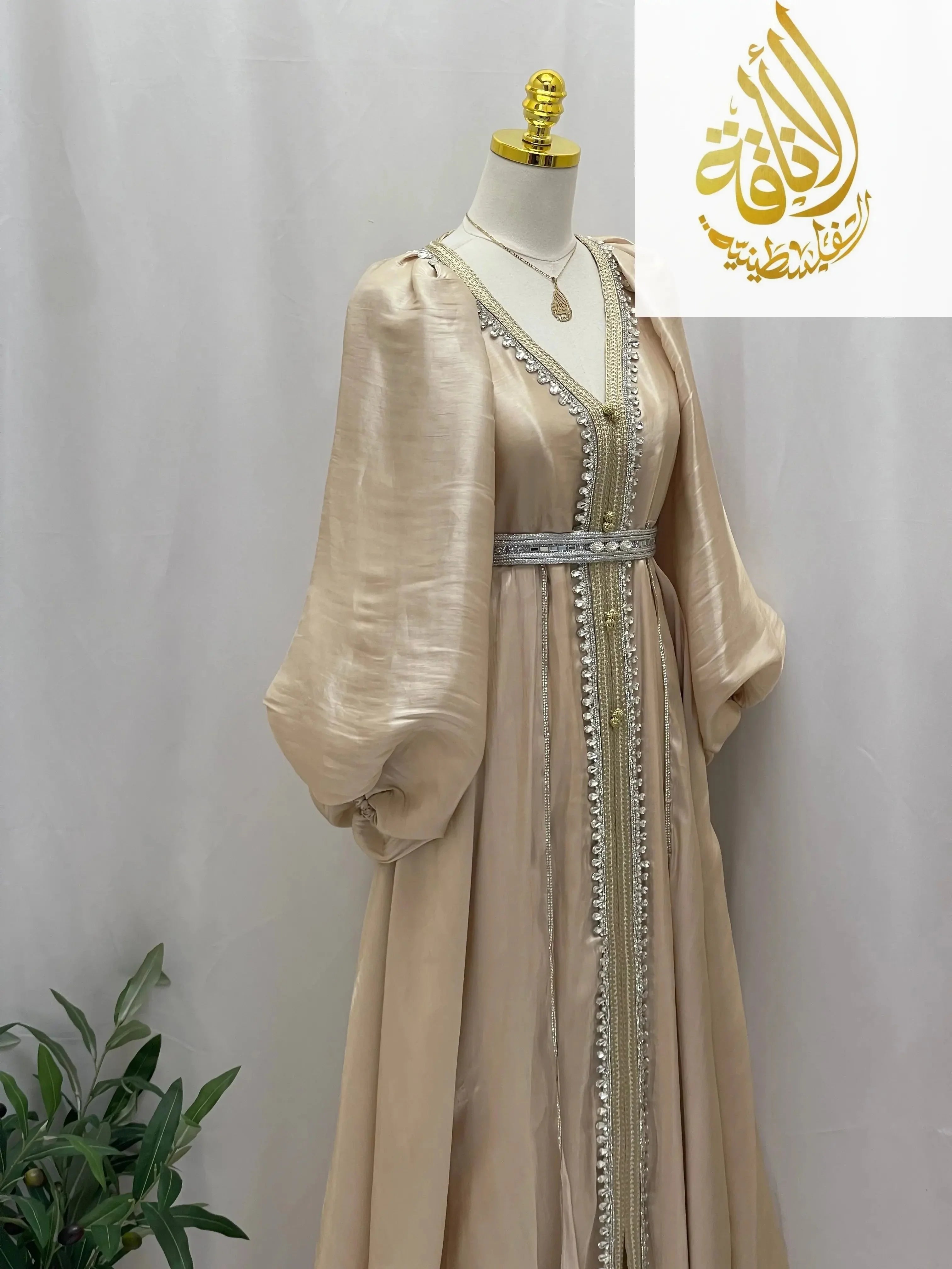 Palestinian Elegance beige puffy sleeves kaftan dress with silver embroidery and belt on mannequin