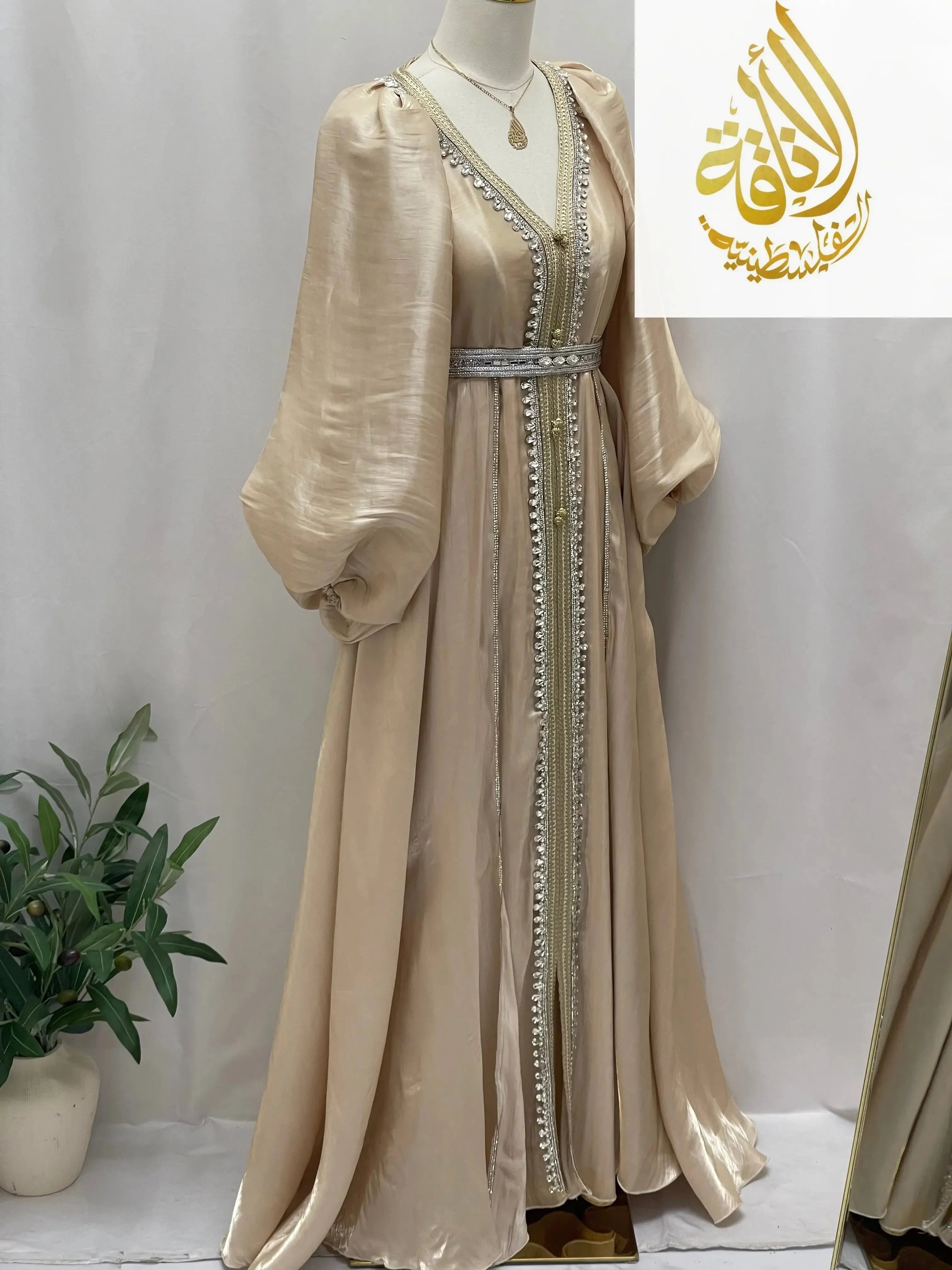 Palestinian Elegance beige puffy sleeves kaftan dress with silver detailing and waist belt on mannequin