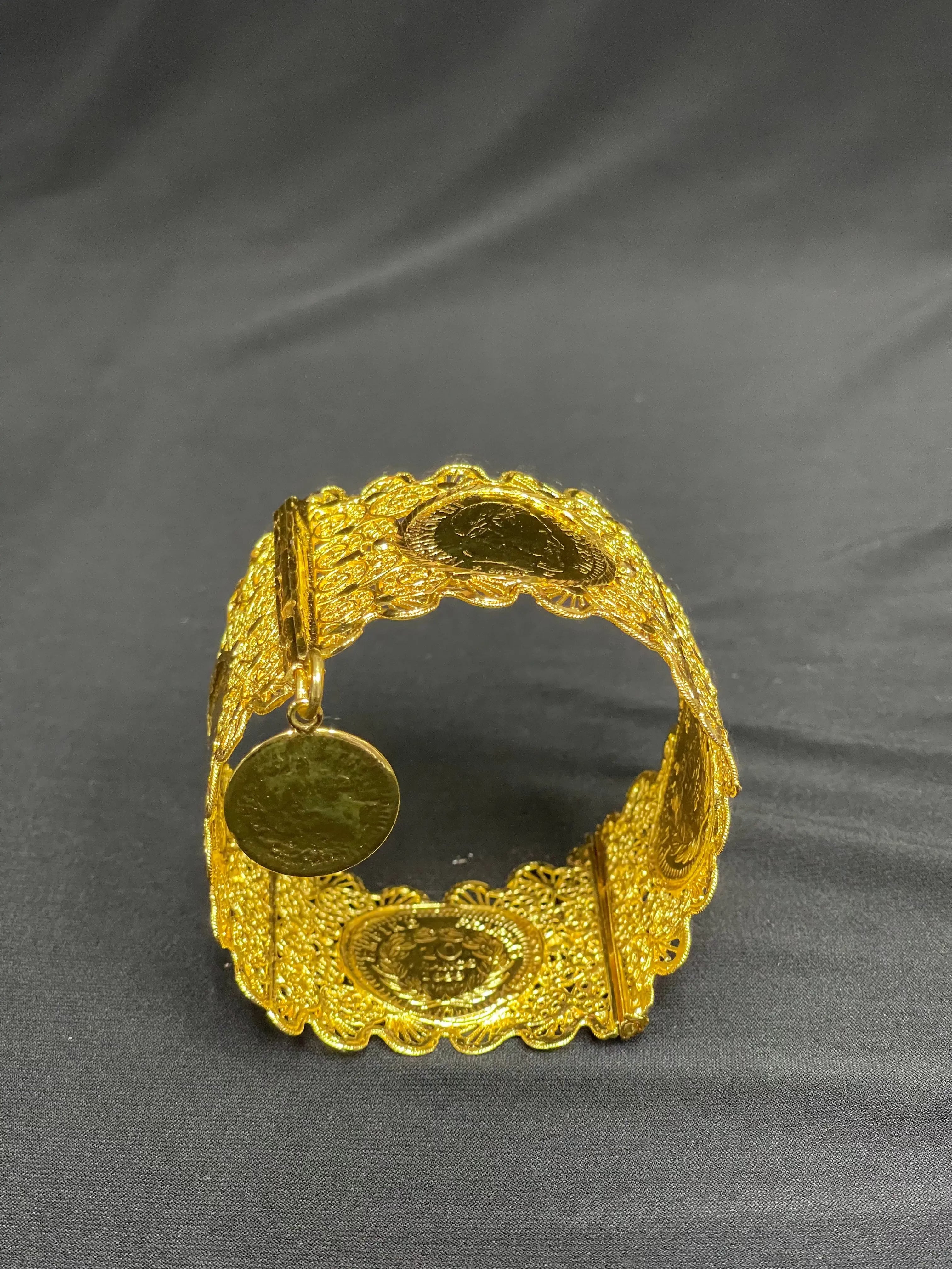 Qamar Bracelet in Imitated Gold by Palestinian Elegance with intricate coin design on black background