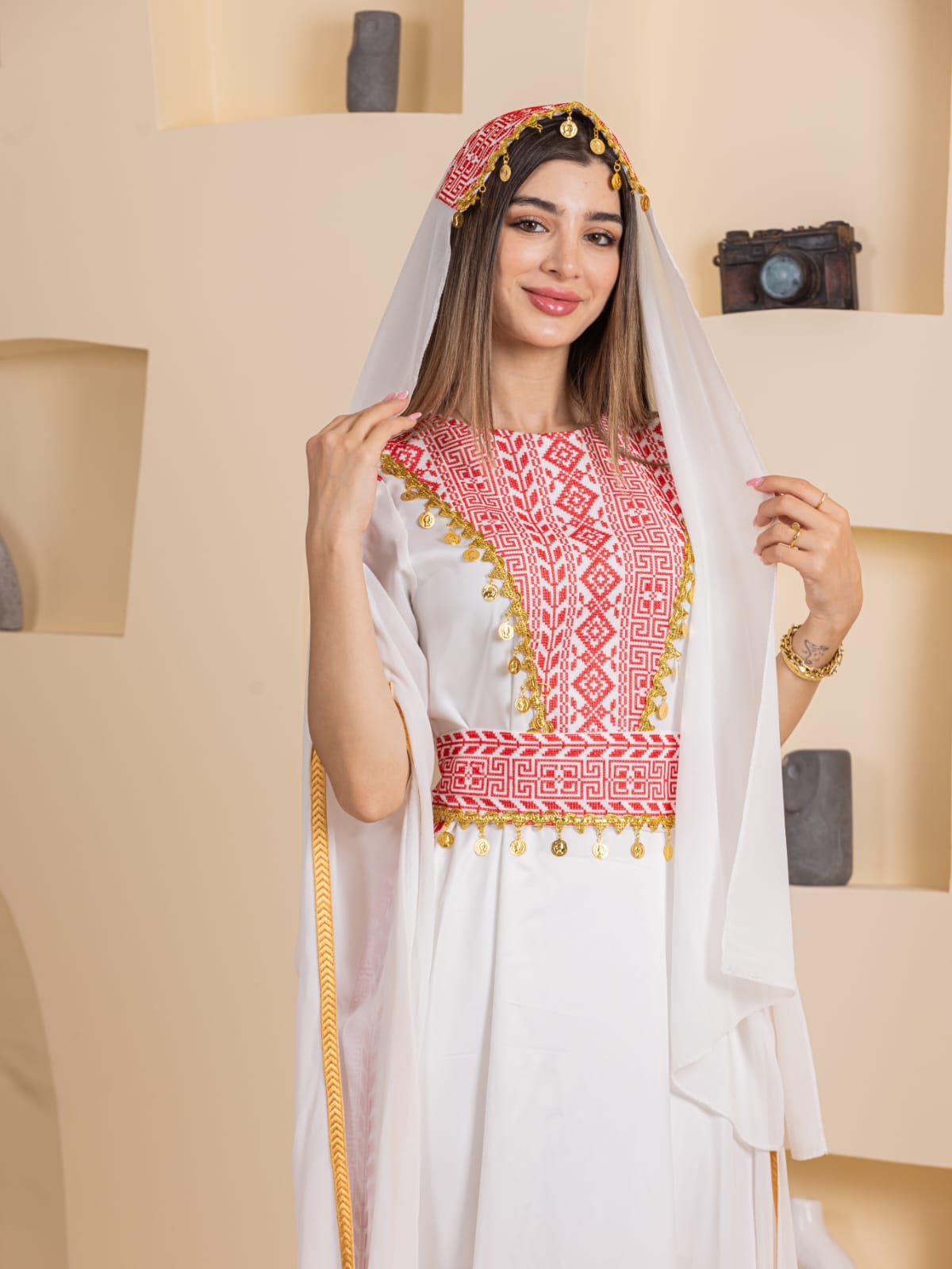 Model wearing Palestinian Elegance Qamar Embroidered Dress white gown with red embroidery and gold trim