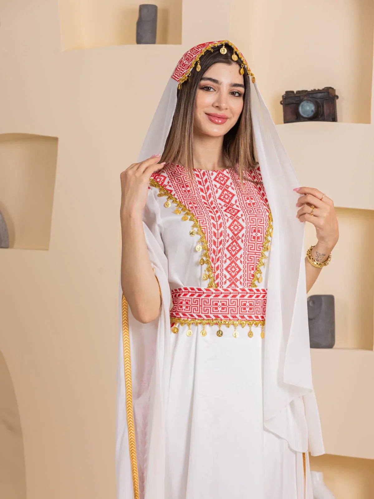 Model wearing Palestinian Elegance Qamar Embroidered Dress white gown with red embroidery and gold trim
