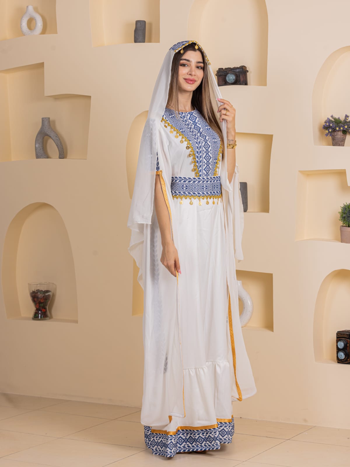 Model wearing Qamar Embroidered Dress white full length gown with blue embroidery and gold trim hooded