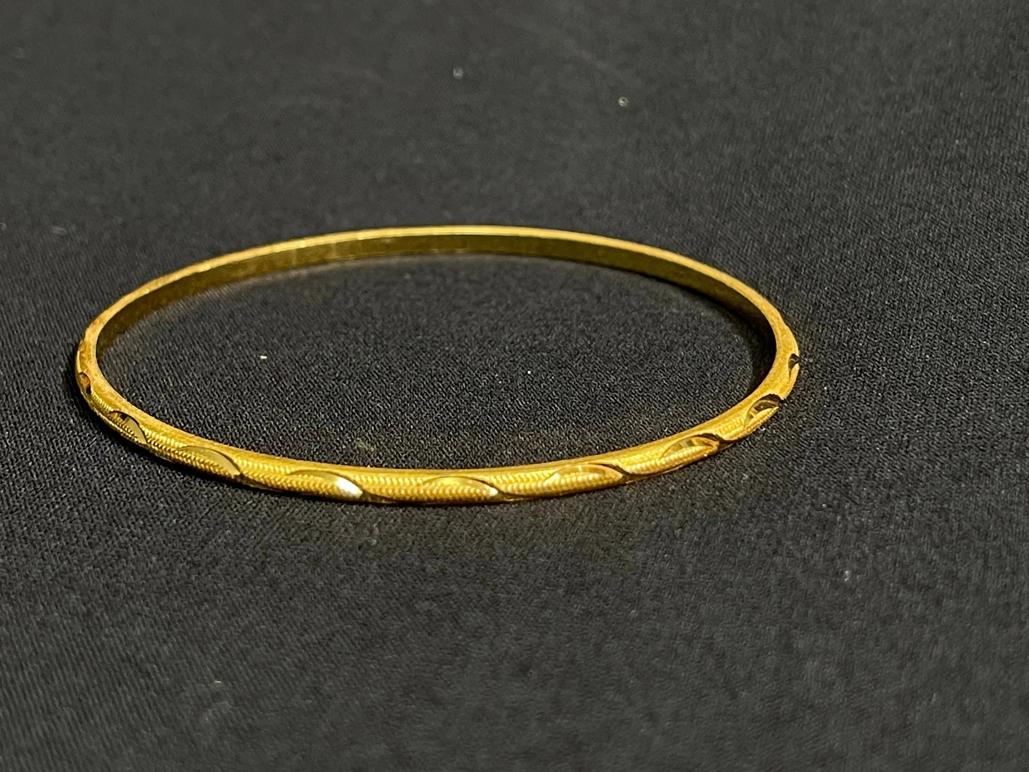 Qamar Thin Bangles Set of 8 imitated gold slim bangles with intricate patterns on black background