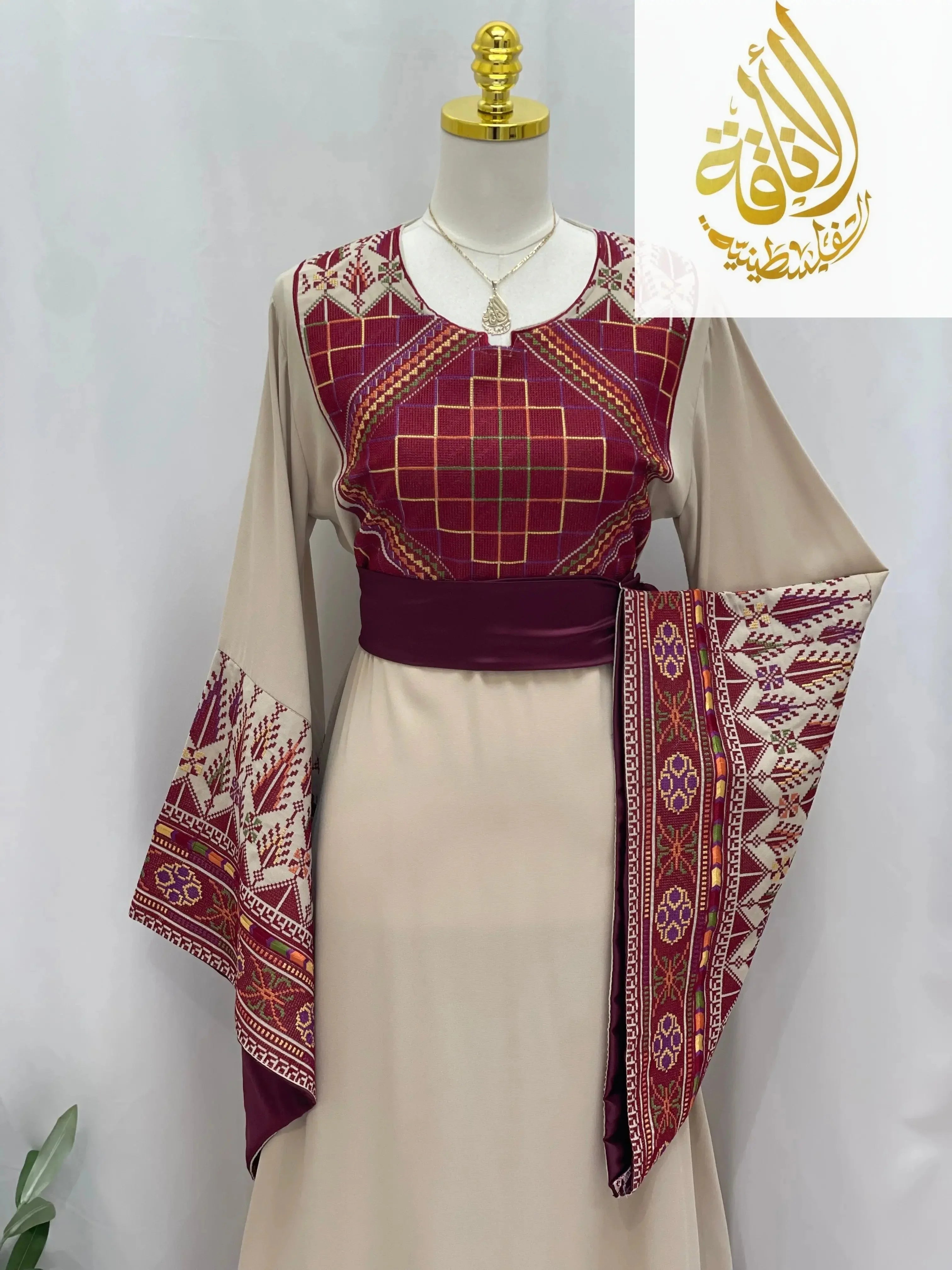 Randa Embroidered Thoub by Palestinian Elegance featuring beige fabric with detailed maroon embroidery and wide sleeves