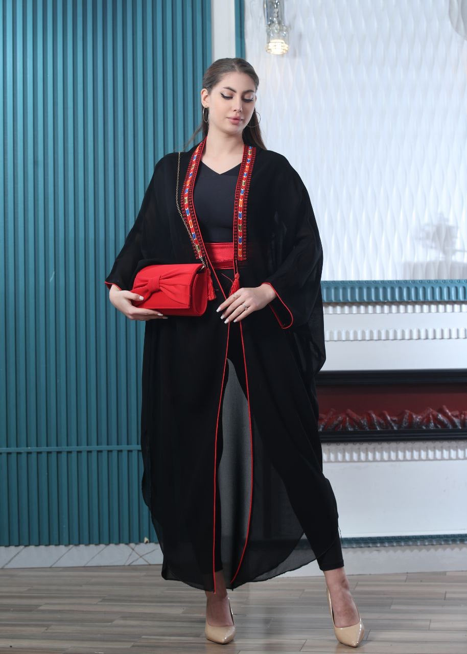 Palestinian Elegance embroidered chiffon cardigan in black with red trim worn with a red clutch and beige heels