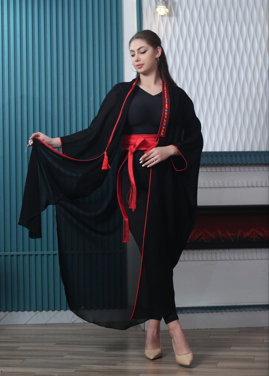 Palestinian Elegance black embroidered chiffon cardigan with red trim worn by woman with red belt