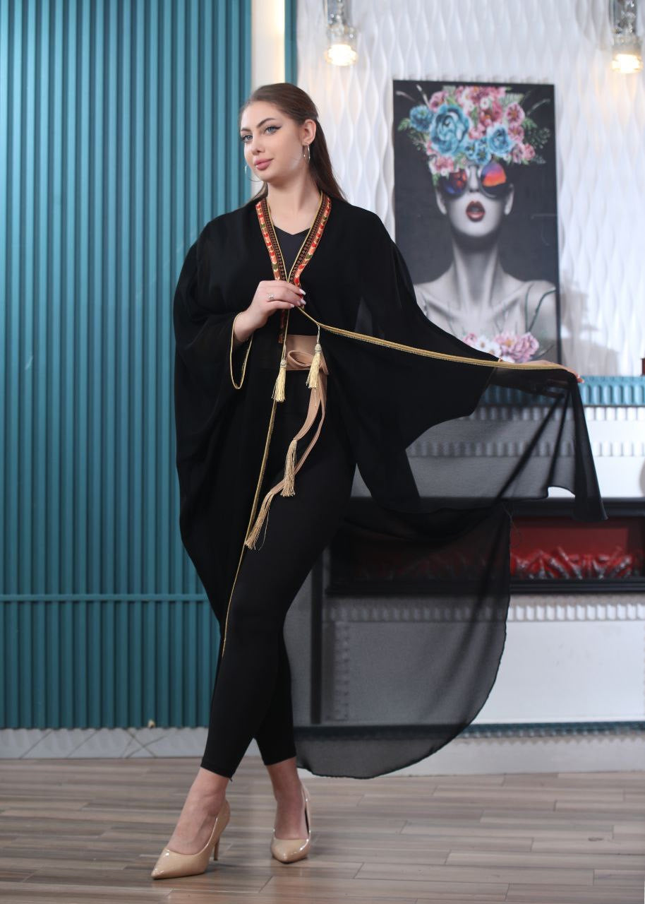 Palestinian Elegance black embroidered chiffon cardigan with gold trim worn by model indoors