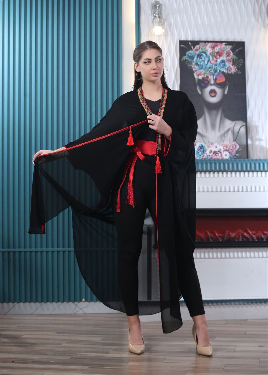 Palestinian Elegance embroidered chiffon cardigan in black with red trim worn by model indoors