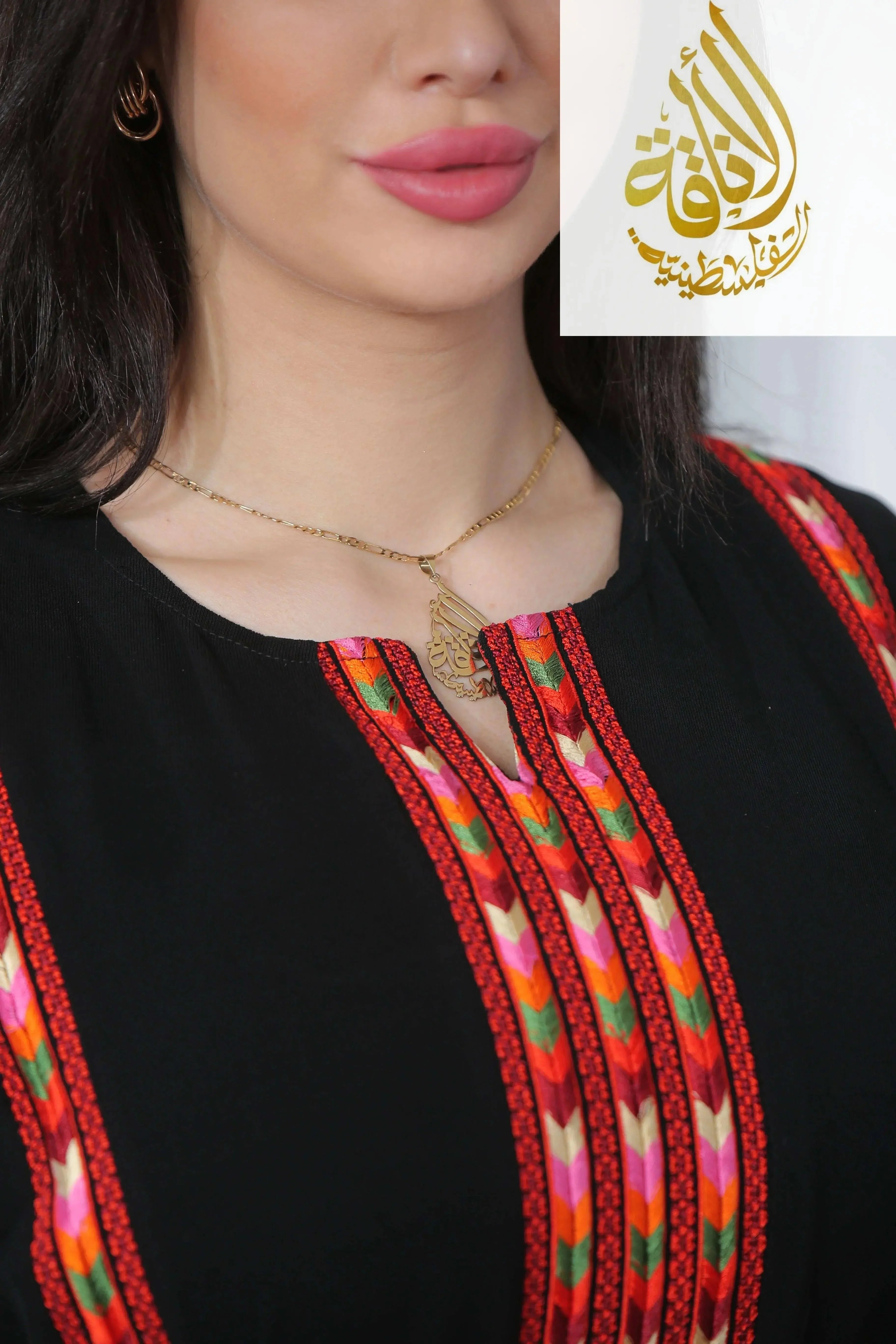 Close-up of Salam Manjal Embroidered Thoub with vibrant red and multicolor traditional embroidery on black fabric by Palestinian Elegance