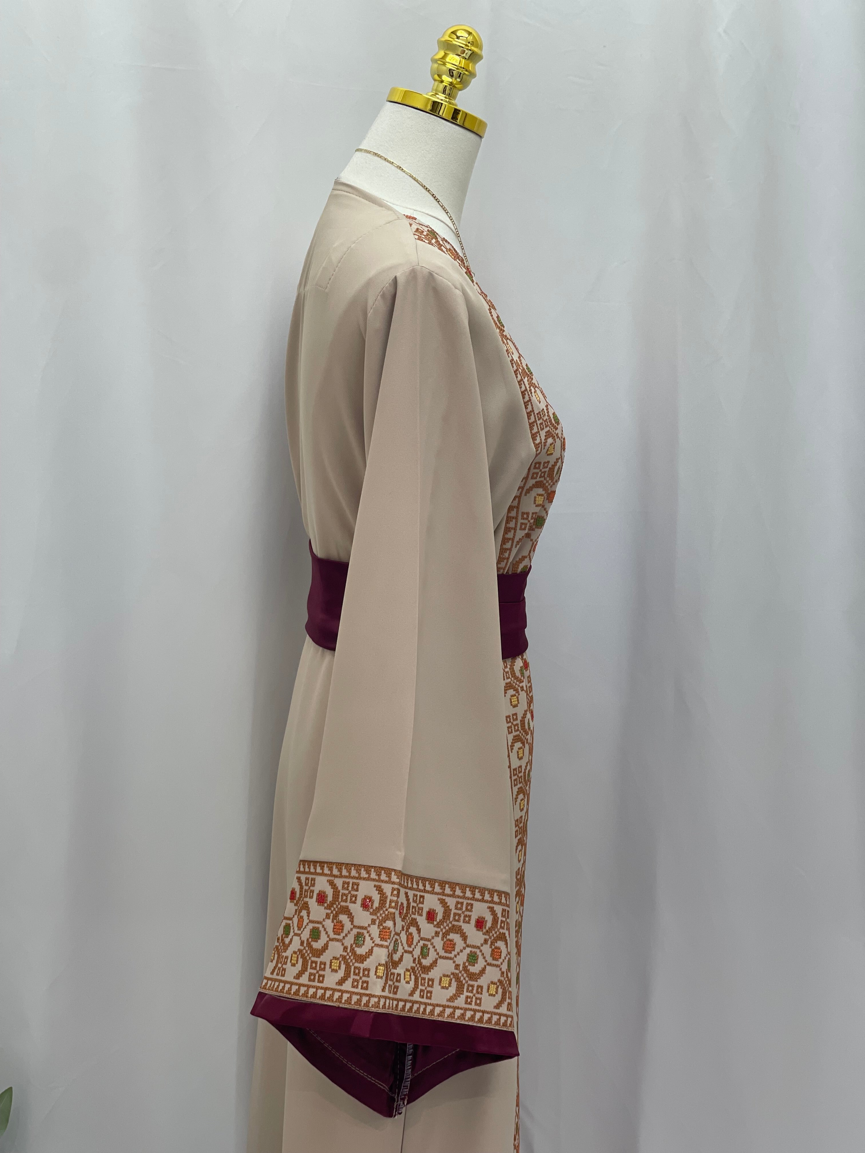 Embroiderd Thobe With Belt by Palestinian Elegance in beige with intricate sleeve embroidery and maroon waist belt