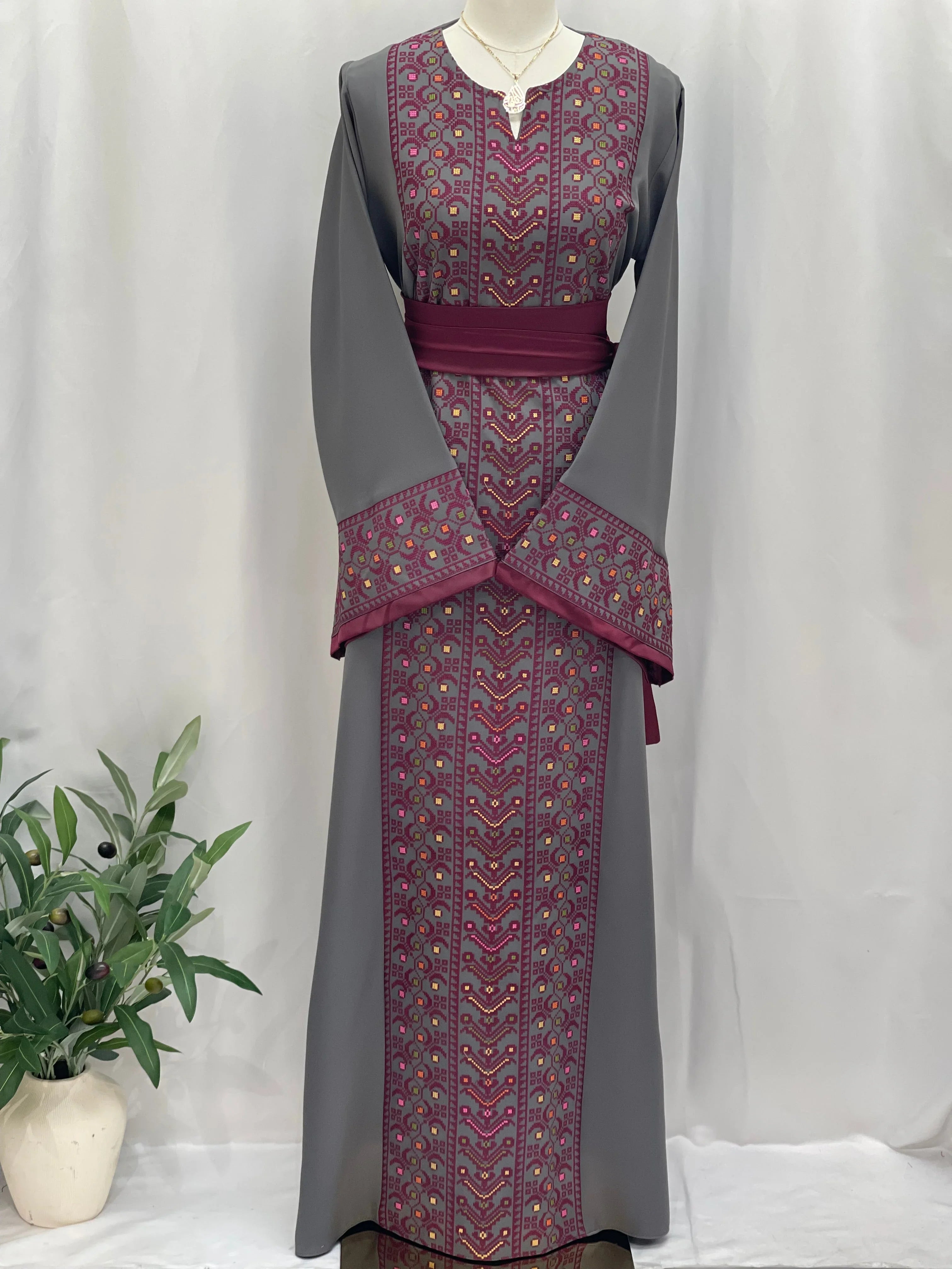 Palestinian Elegance Embroiderd Thobe With Belt featuring intricate maroon and gold embroidery on gray fabric