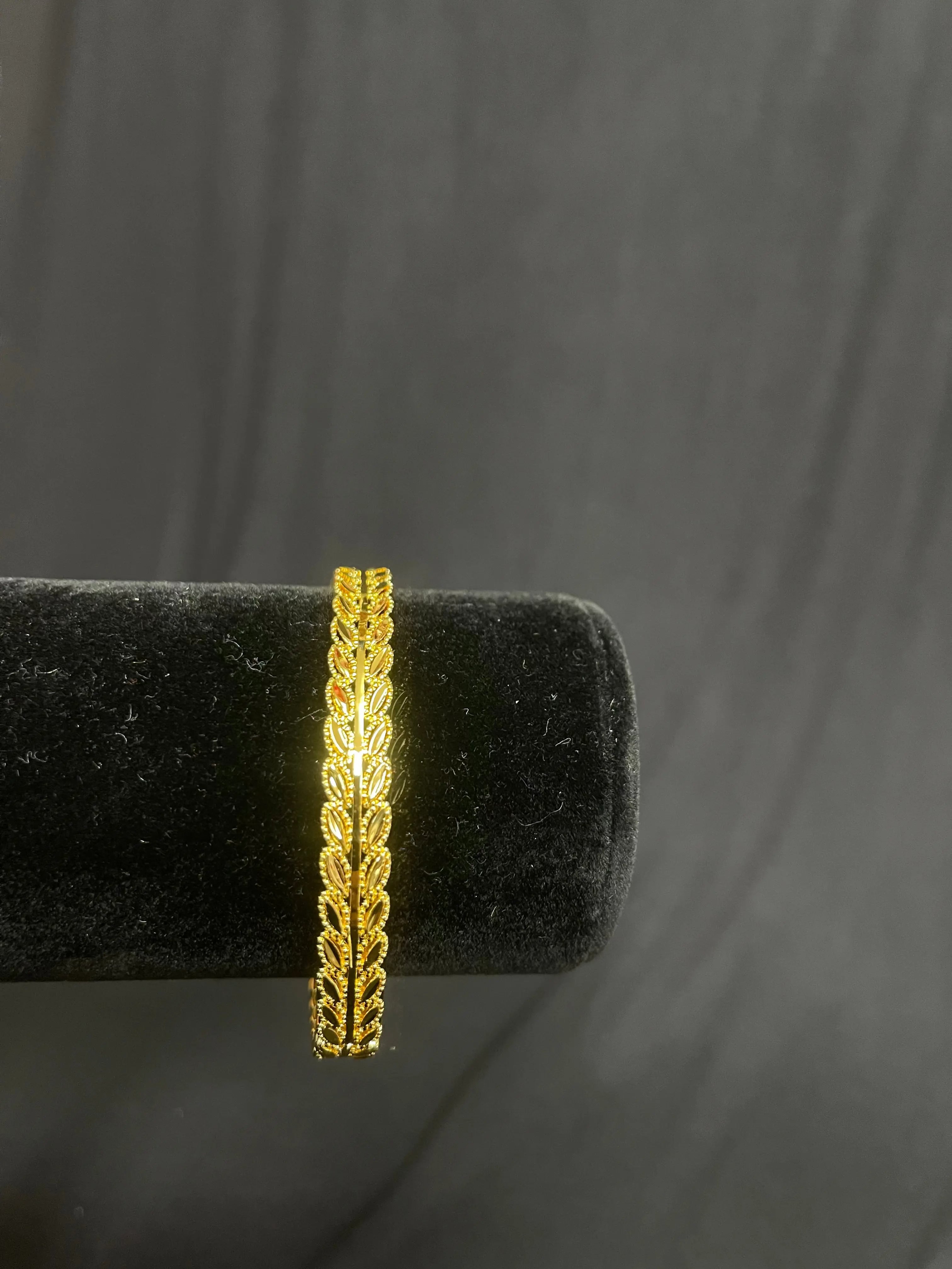 Palestinian Elegance imitation gold bangle bracelet with intricate leaf design on black display