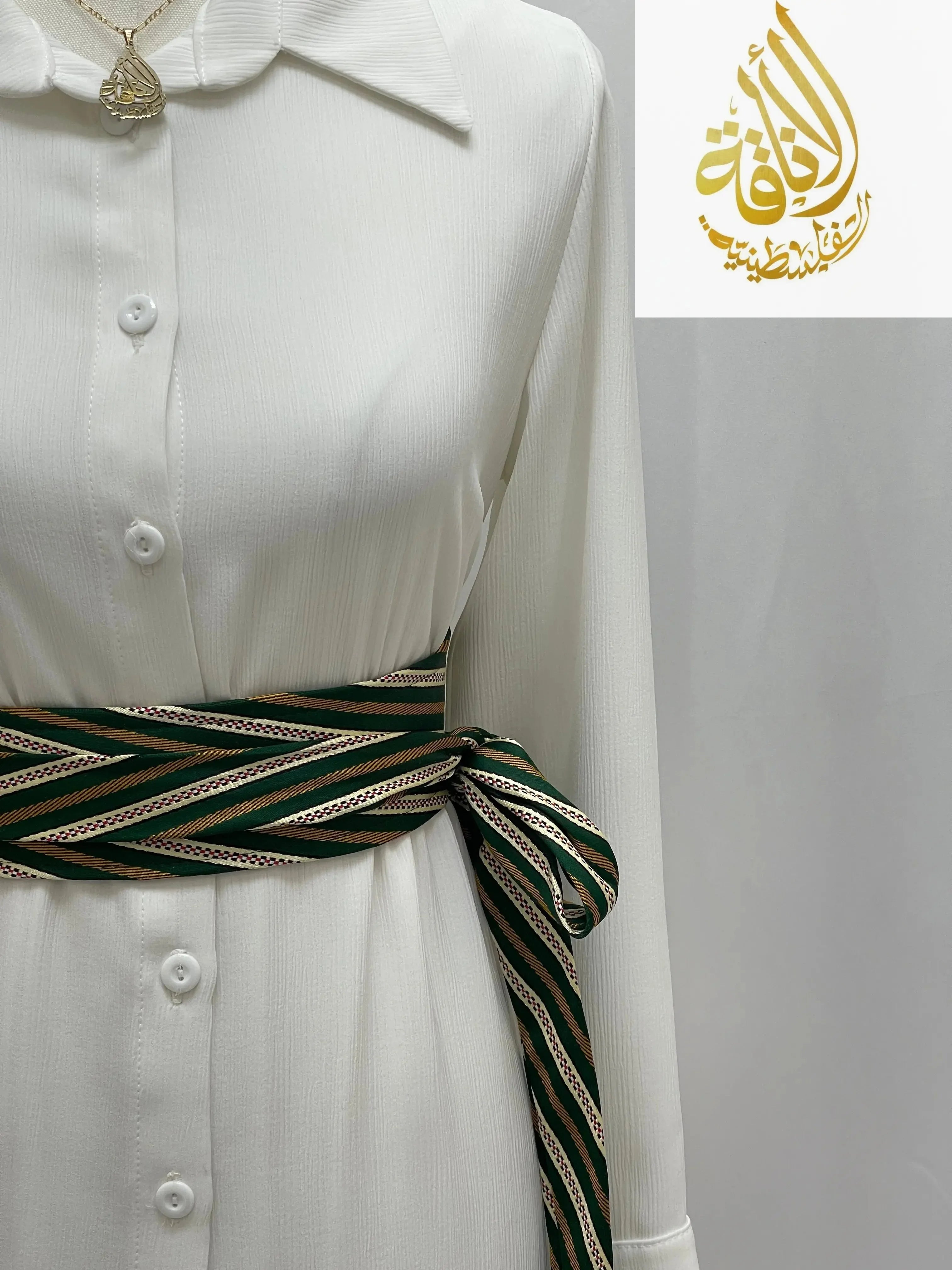 Palestinian embroidered belt with green and beige stripes tied around a white shirt dress