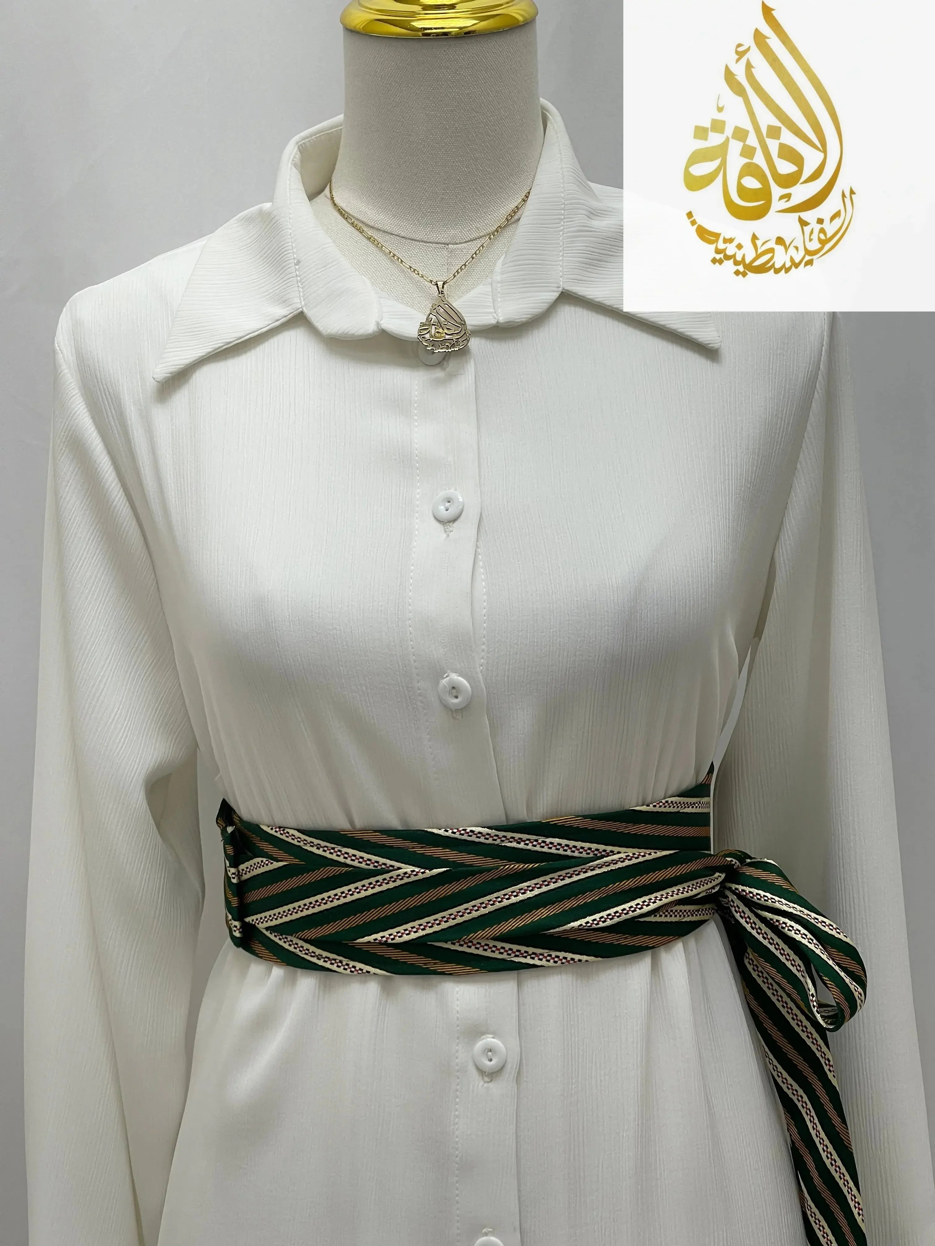 Palestinian embroidered belt in green and beige wrapped around white button-down dress
