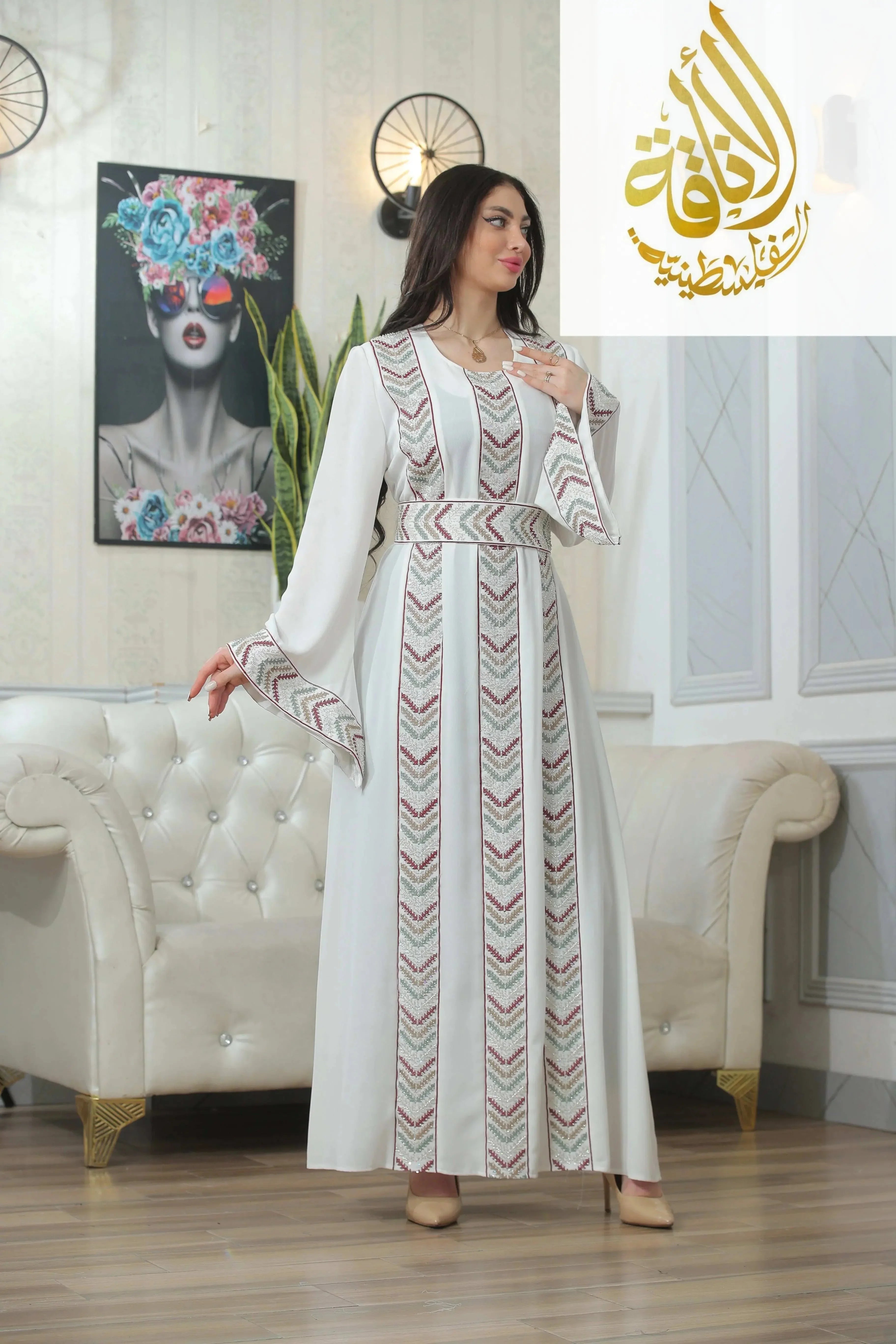Woman wearing a white Seham Embroidered Beads Thoub with patterned vertical embroidery in a modern living room