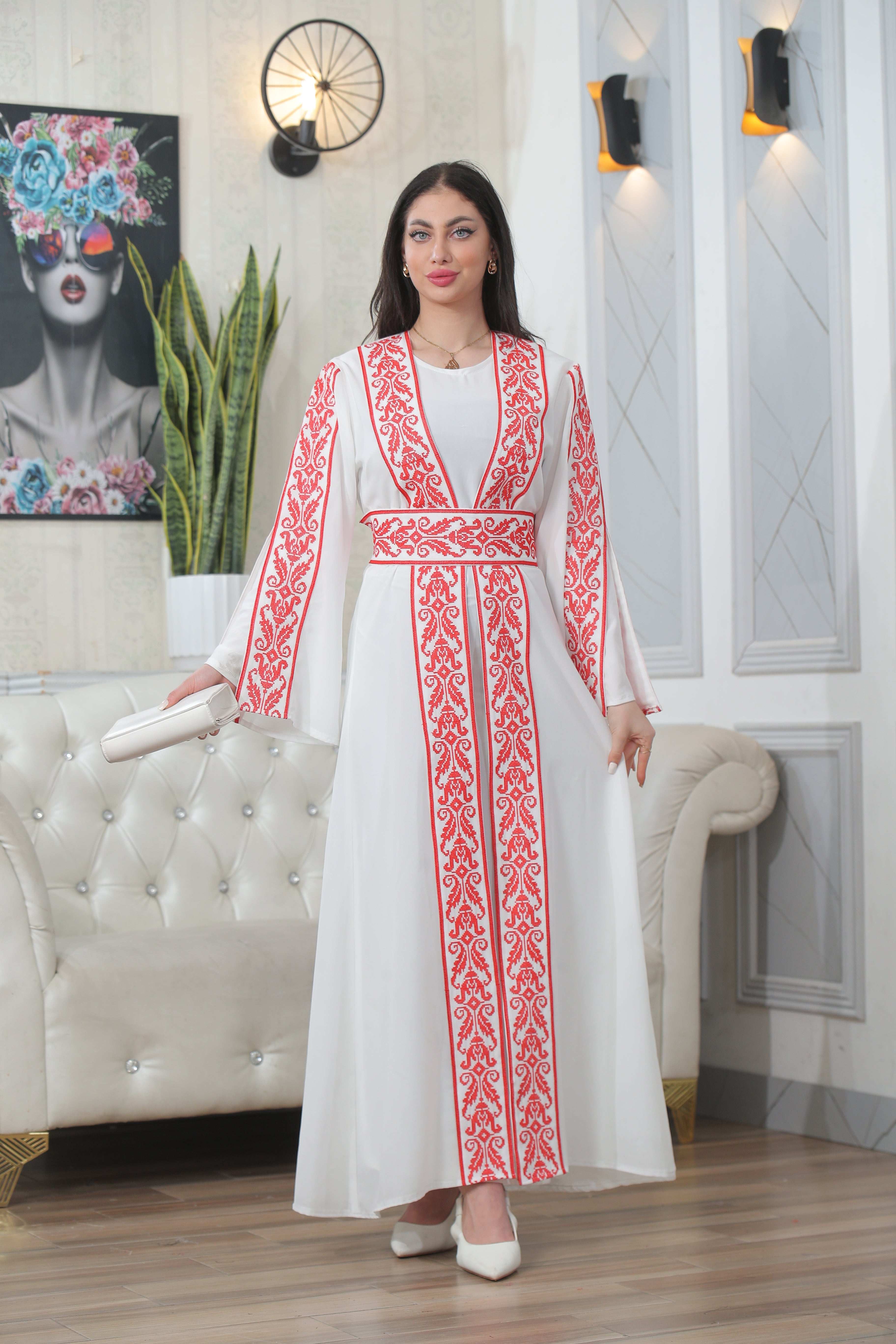 Palestinian Elegance Shereen Embroidered Bisht Abaya in white with red intricate embroidery worn by a woman indoors
