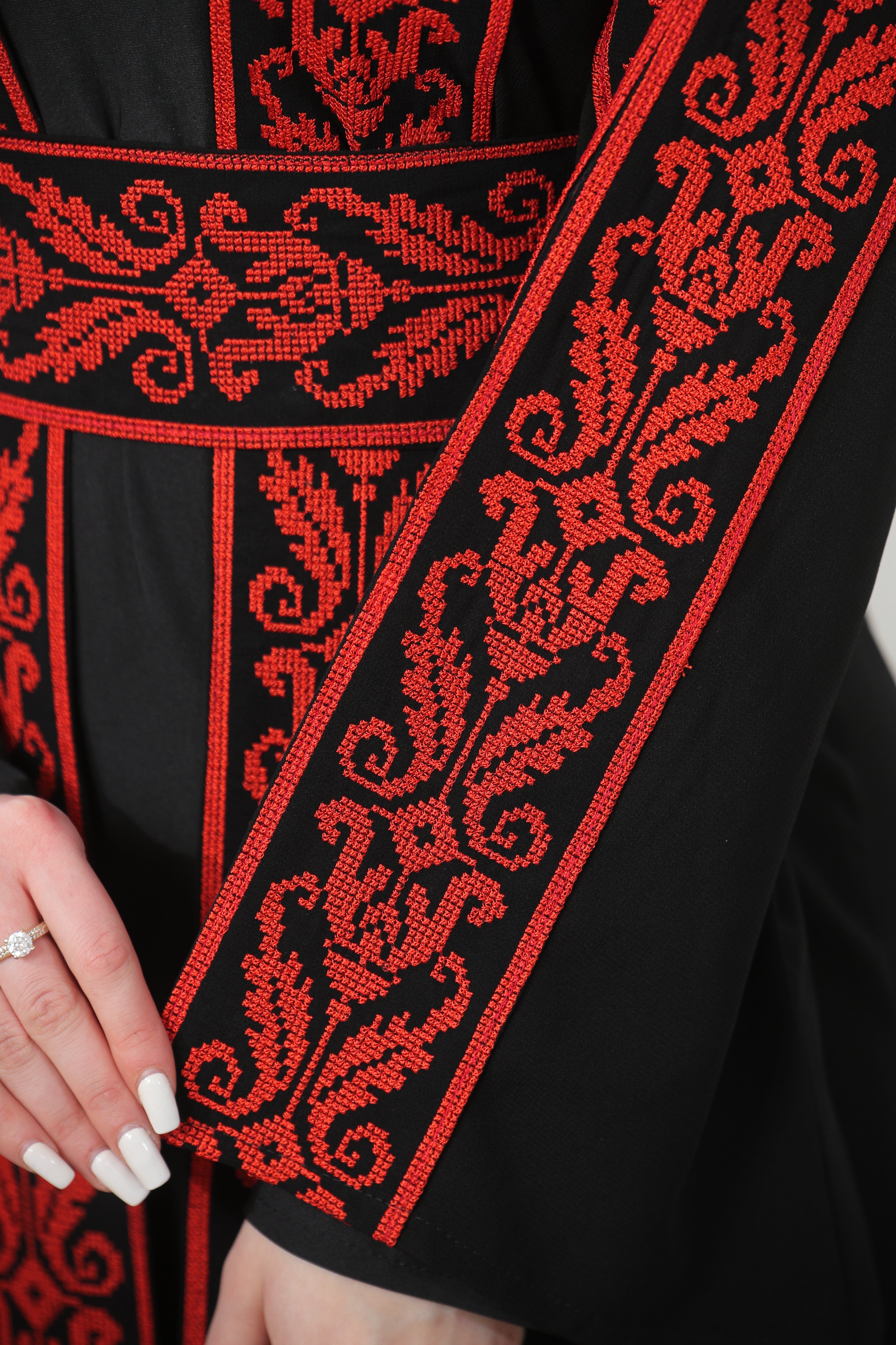 Close-up of Shereen Embroidered Bisht Abaya sleeve and waist detail in red embroidery on black fabric by Palestinian Elegance