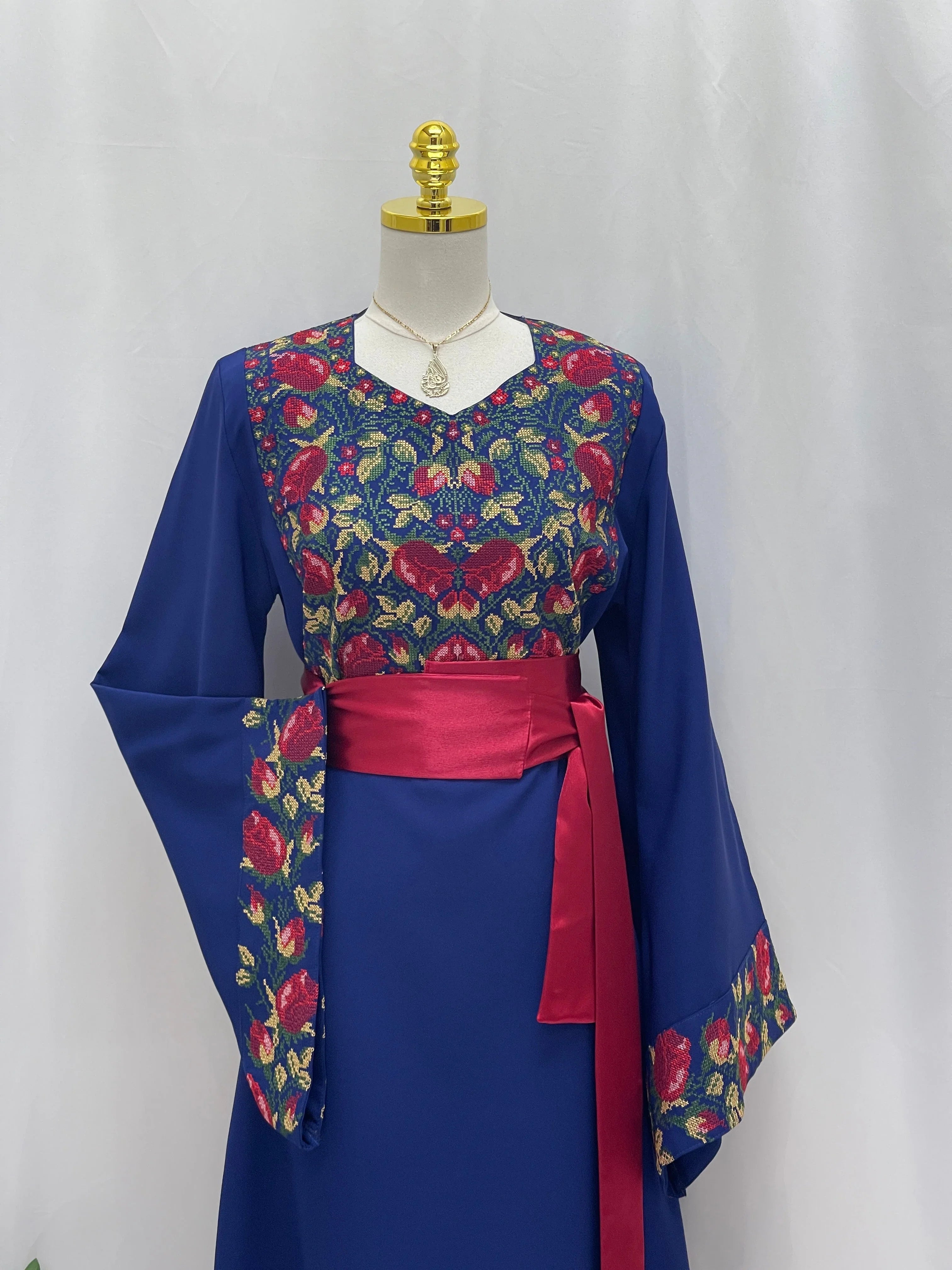 Blossom Royal Blue Thobe Palestinian Elegance embroidered floral yoke and cuffs with red waist sash on mannequin
