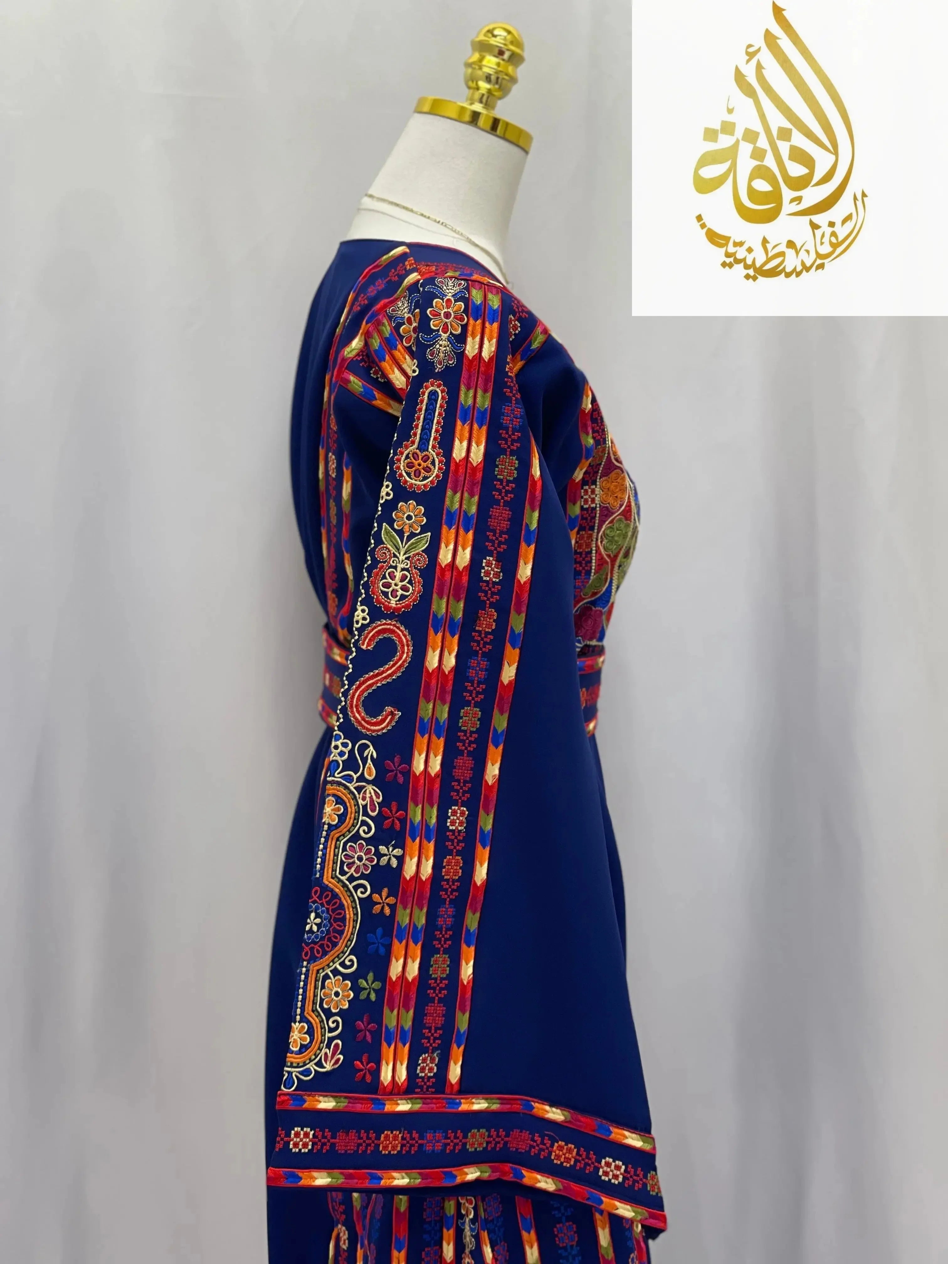 Embroidered Palestinian dress in blue with colorful traditional embroidery displayed on mannequin