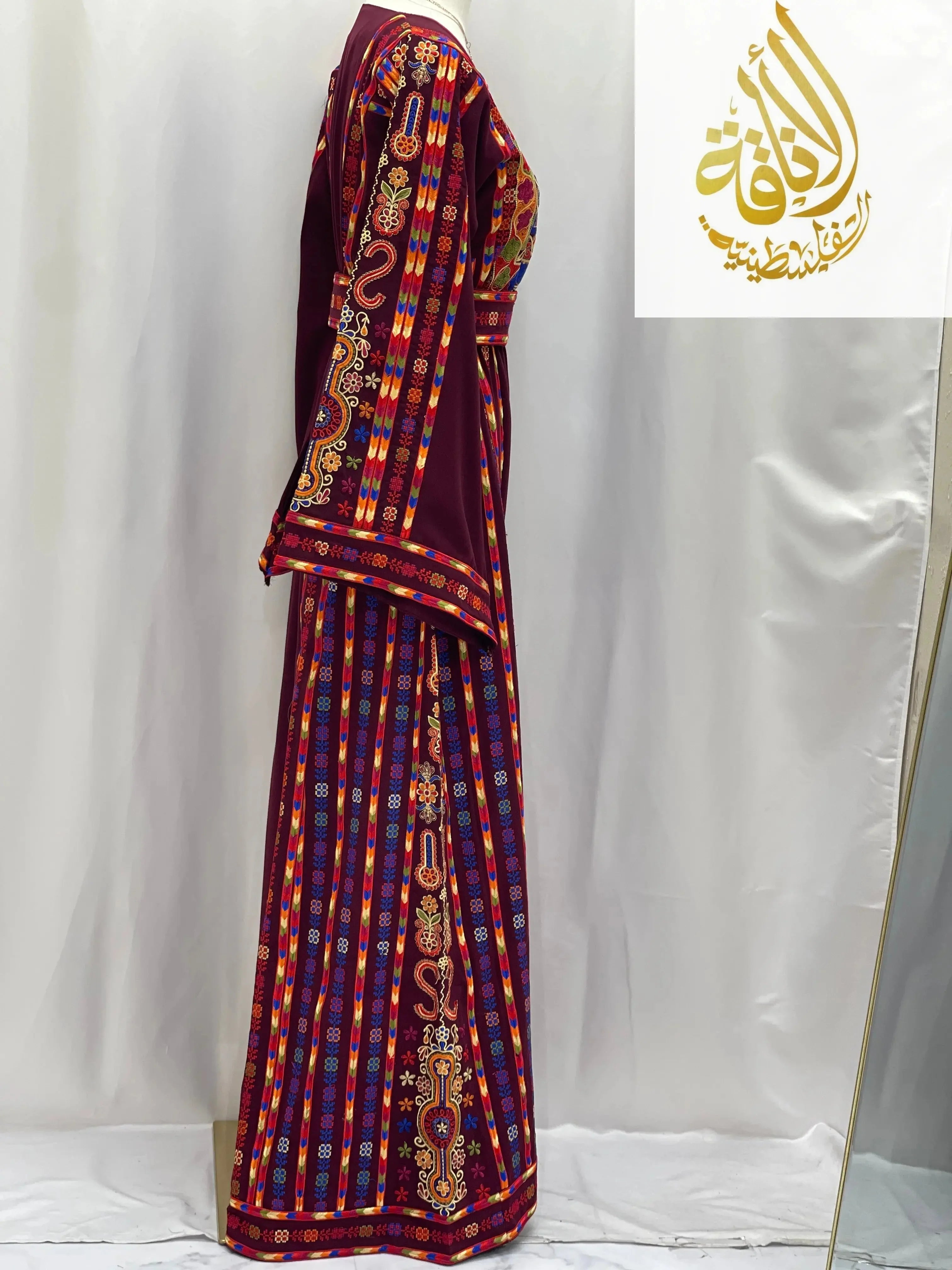 Side view of a vibrant embroidered Palestinian dress featuring intricate traditional patterns and rich colors