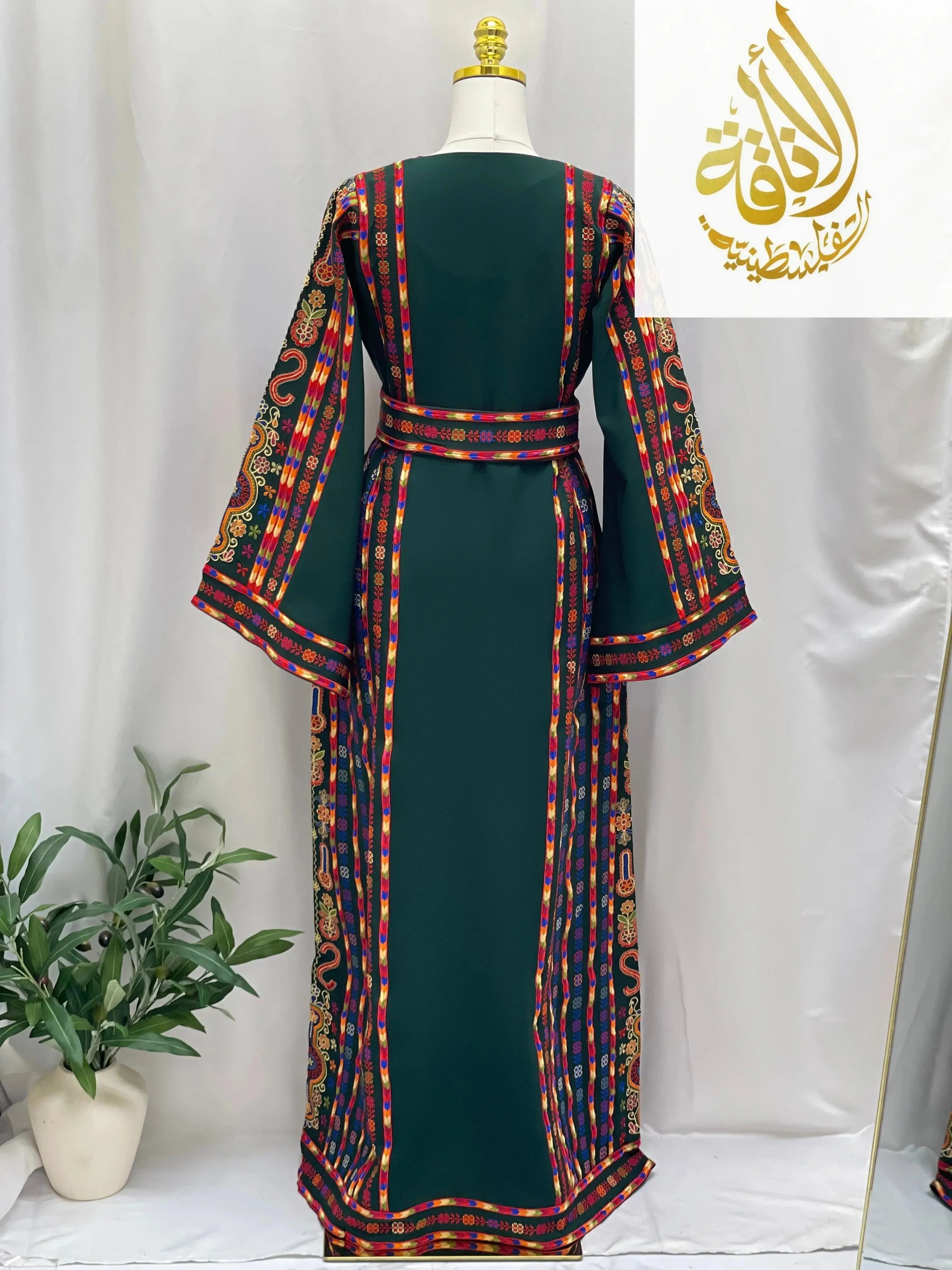 Back view of a green embroidered Palestinian dress with colorful traditional patterns and a matching belt