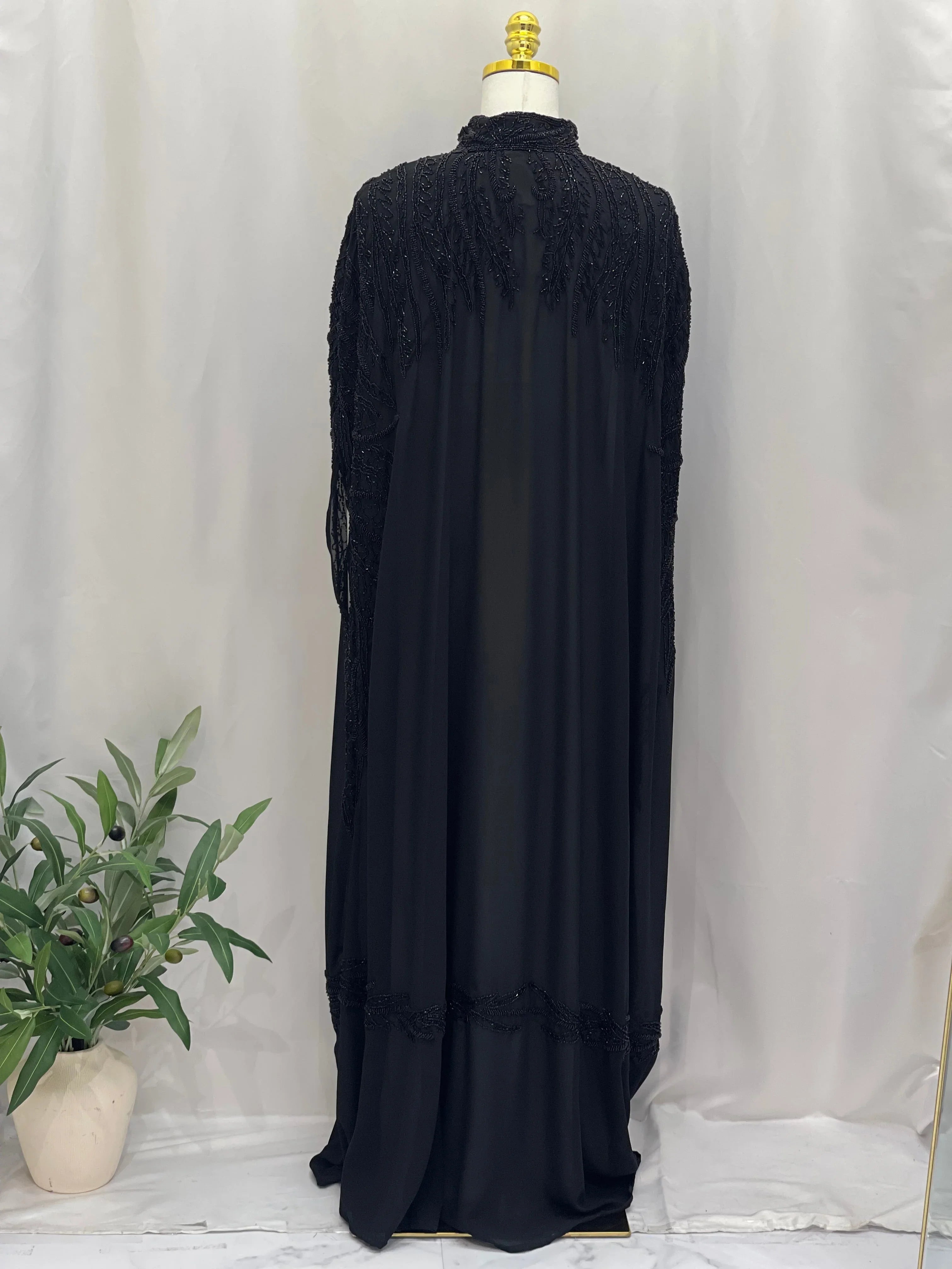 Black traditional embroidery cape with intricate hand-stitched designs displayed on mannequin
