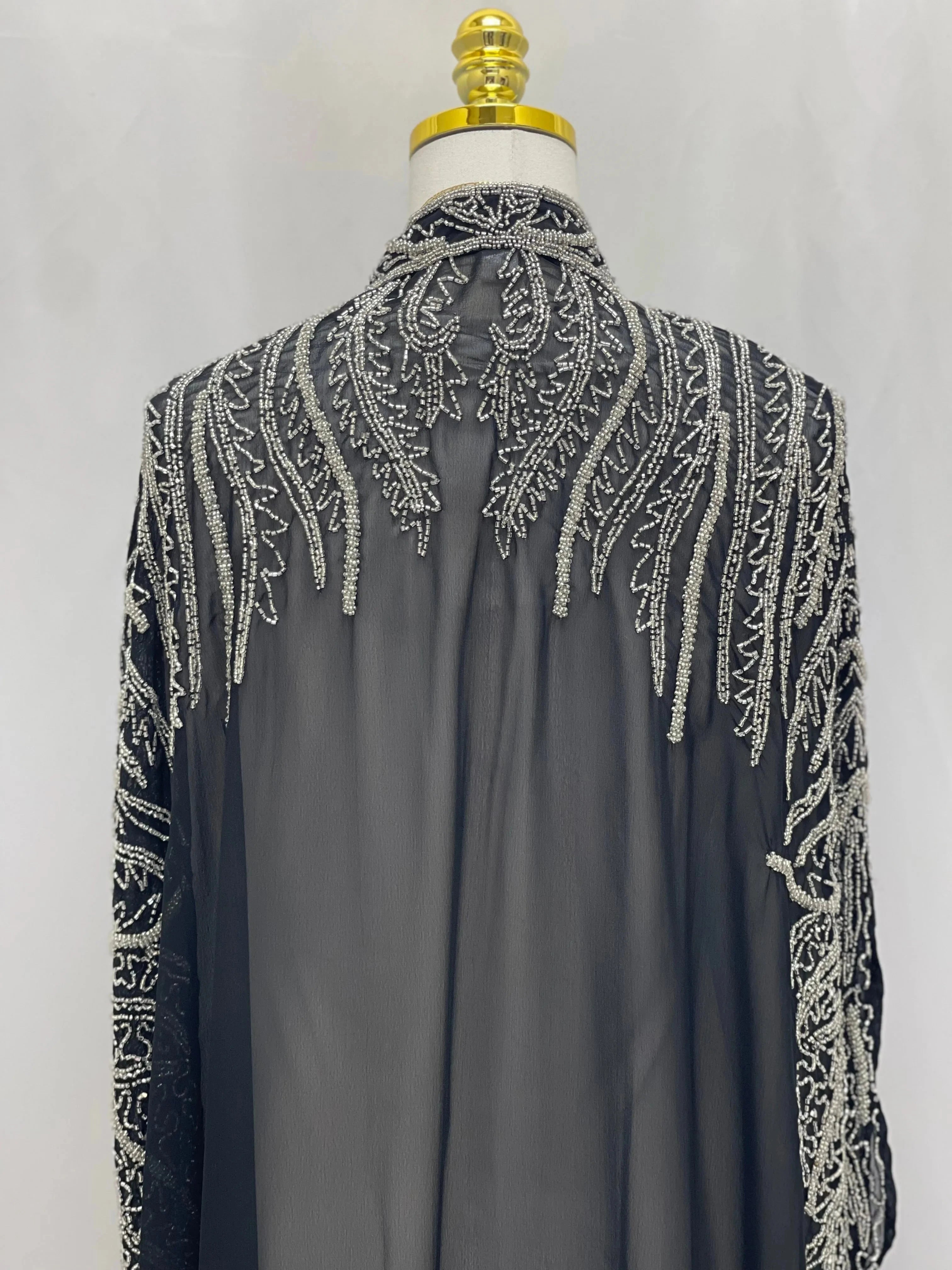 Black traditional embroidery cape with intricate white stitched patterns on sheer fabric by Palestinian Elegance