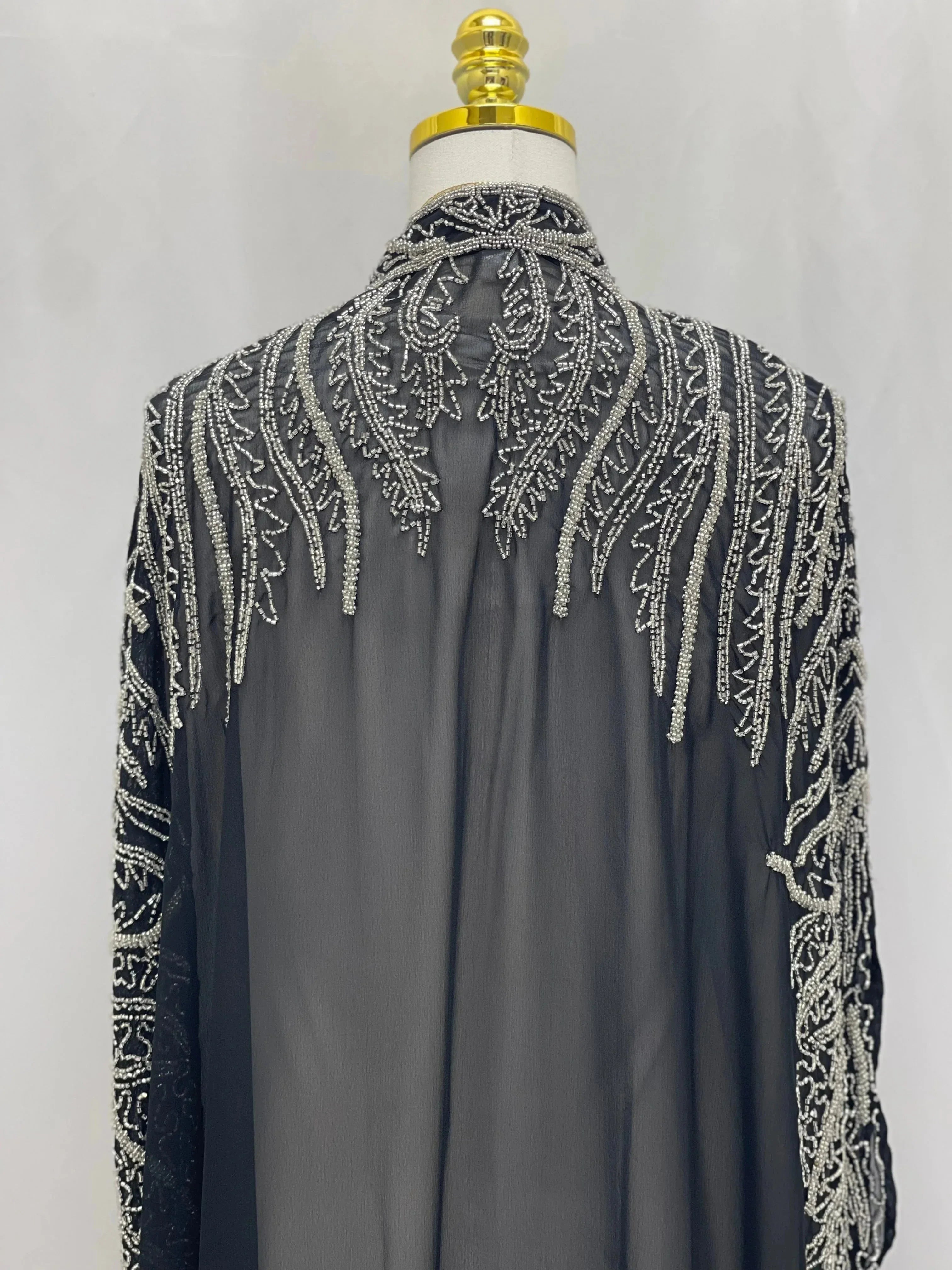 Black traditional embroidery cape with intricate white stitched patterns on sheer fabric by Palestinian Elegance