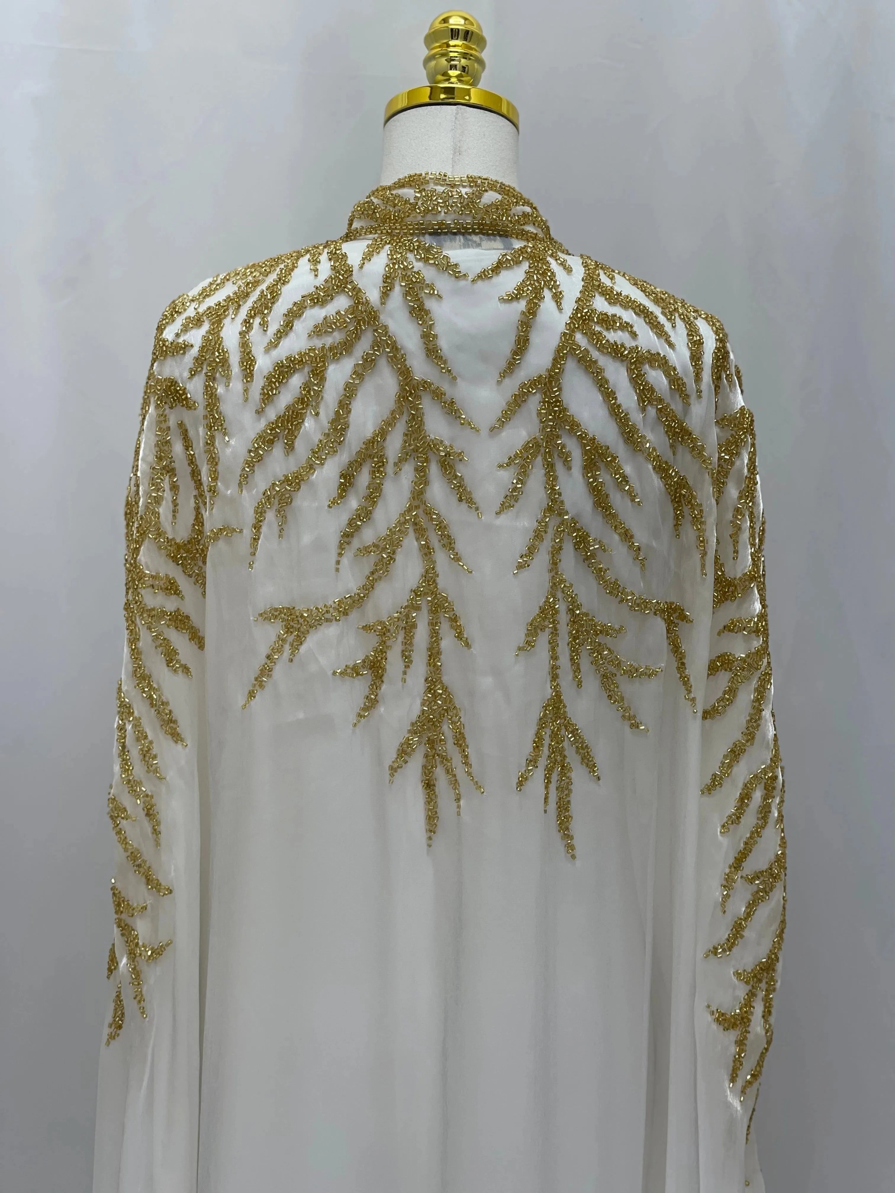 White traditional embroidery cape with intricate gold thread patterns by Palestinian Elegance