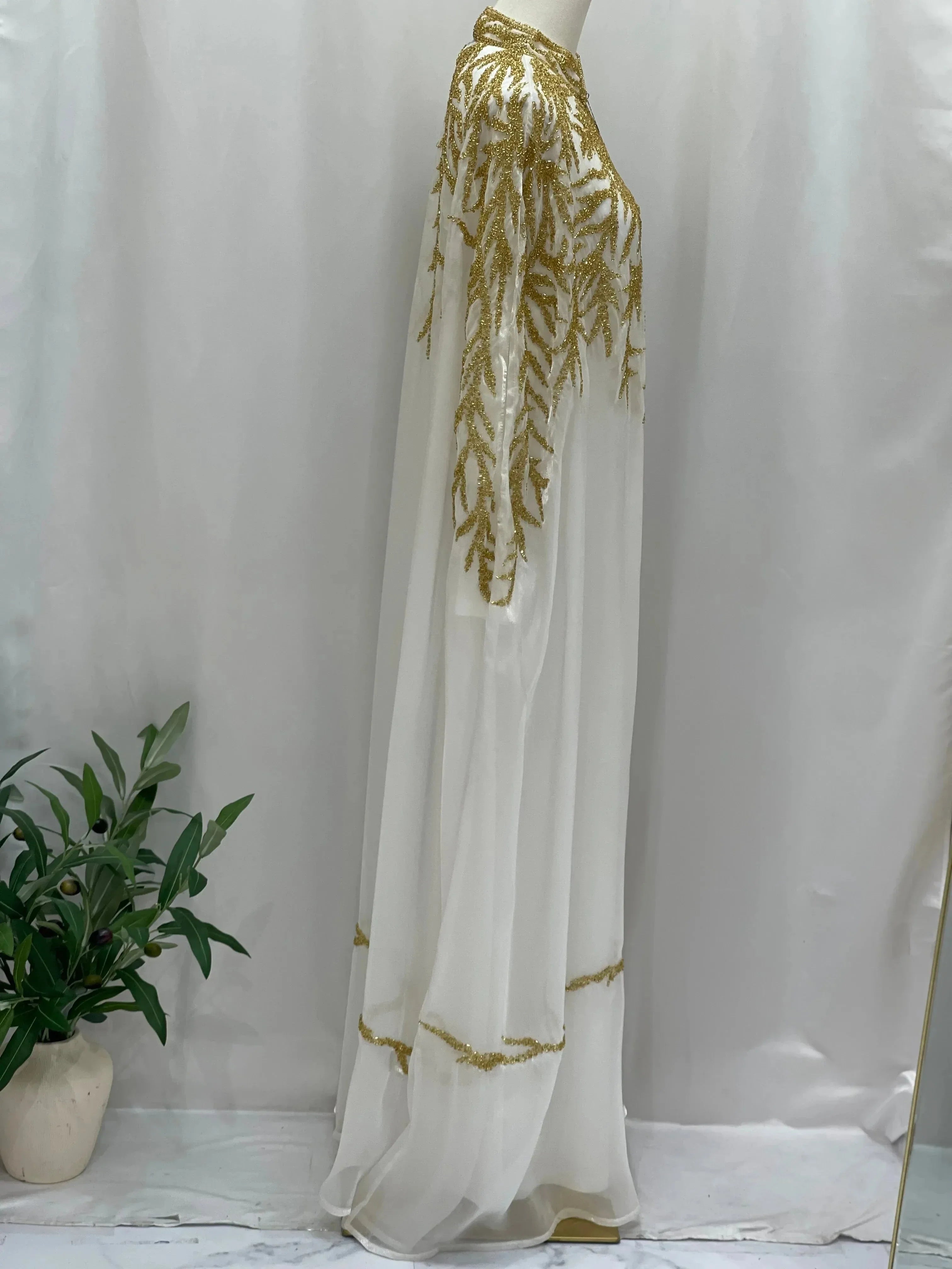 White traditional embroidery cape with intricate gold detailing by Palestinian Elegance displayed on mannequin