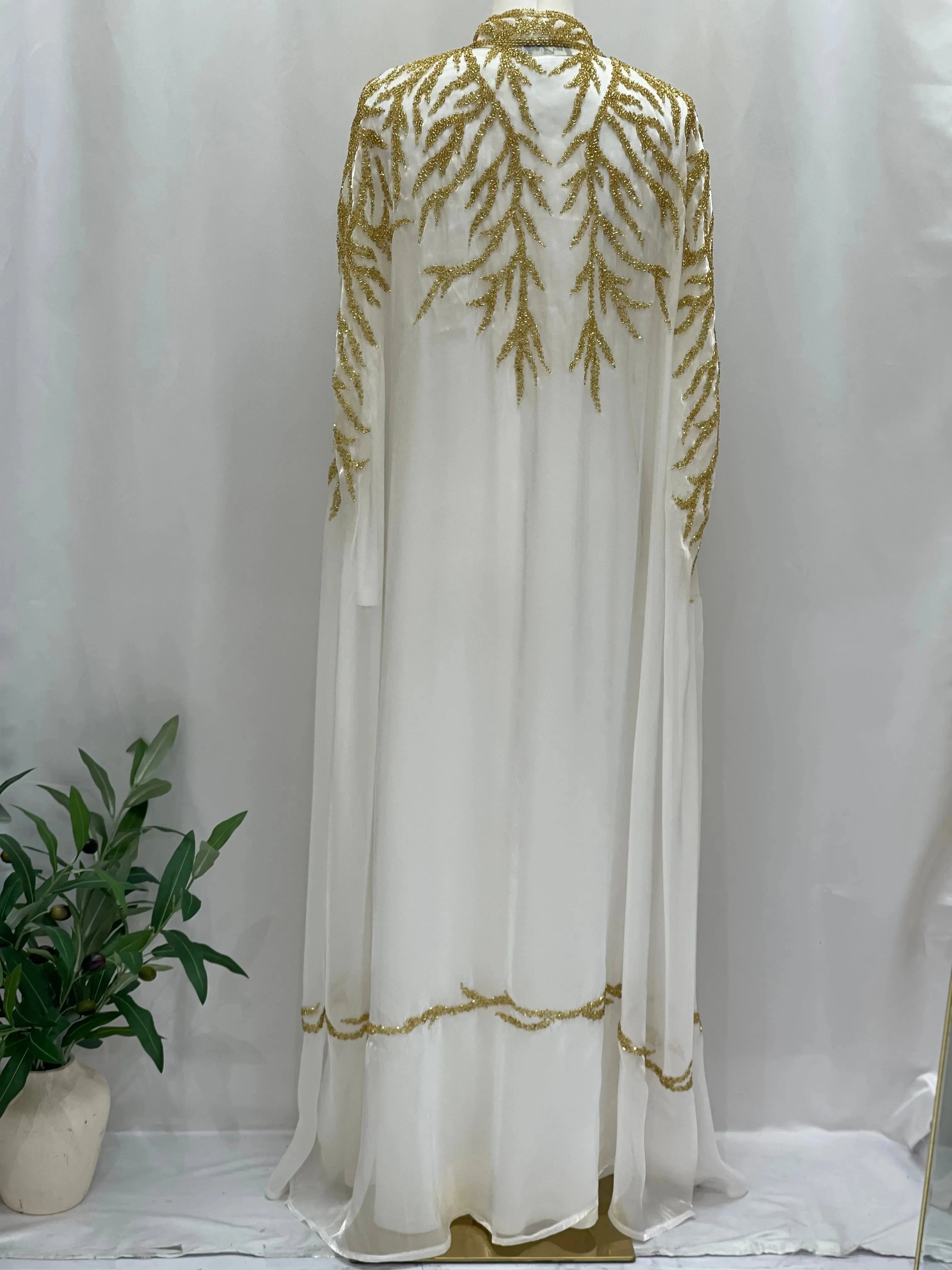 White traditional embroidery cape with intricate gold thread designs from Palestinian Elegance