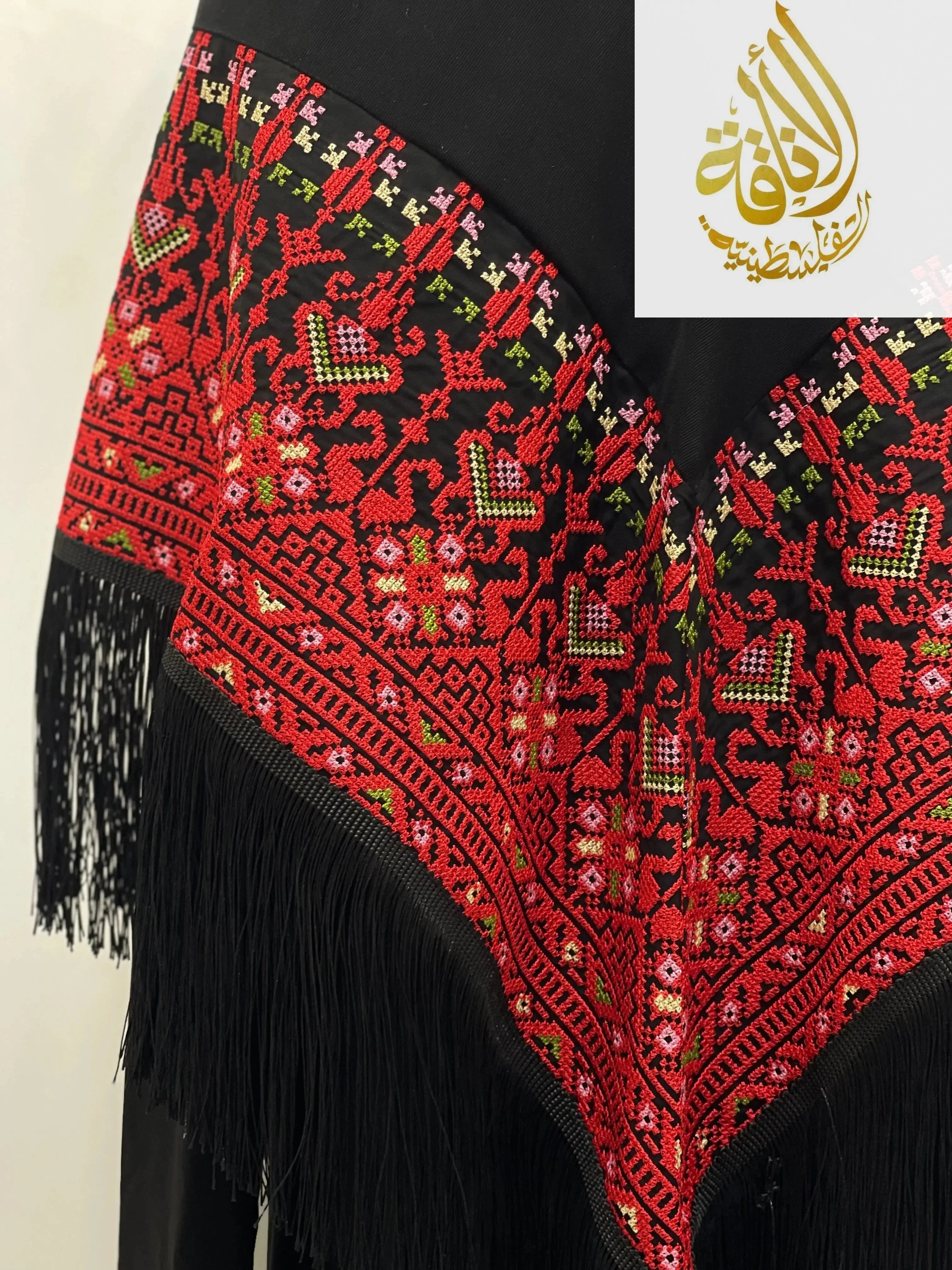 Palestinian embroidered shawl with intricate red, green, and white floral patterns and black fringe by Palestinian Elegance