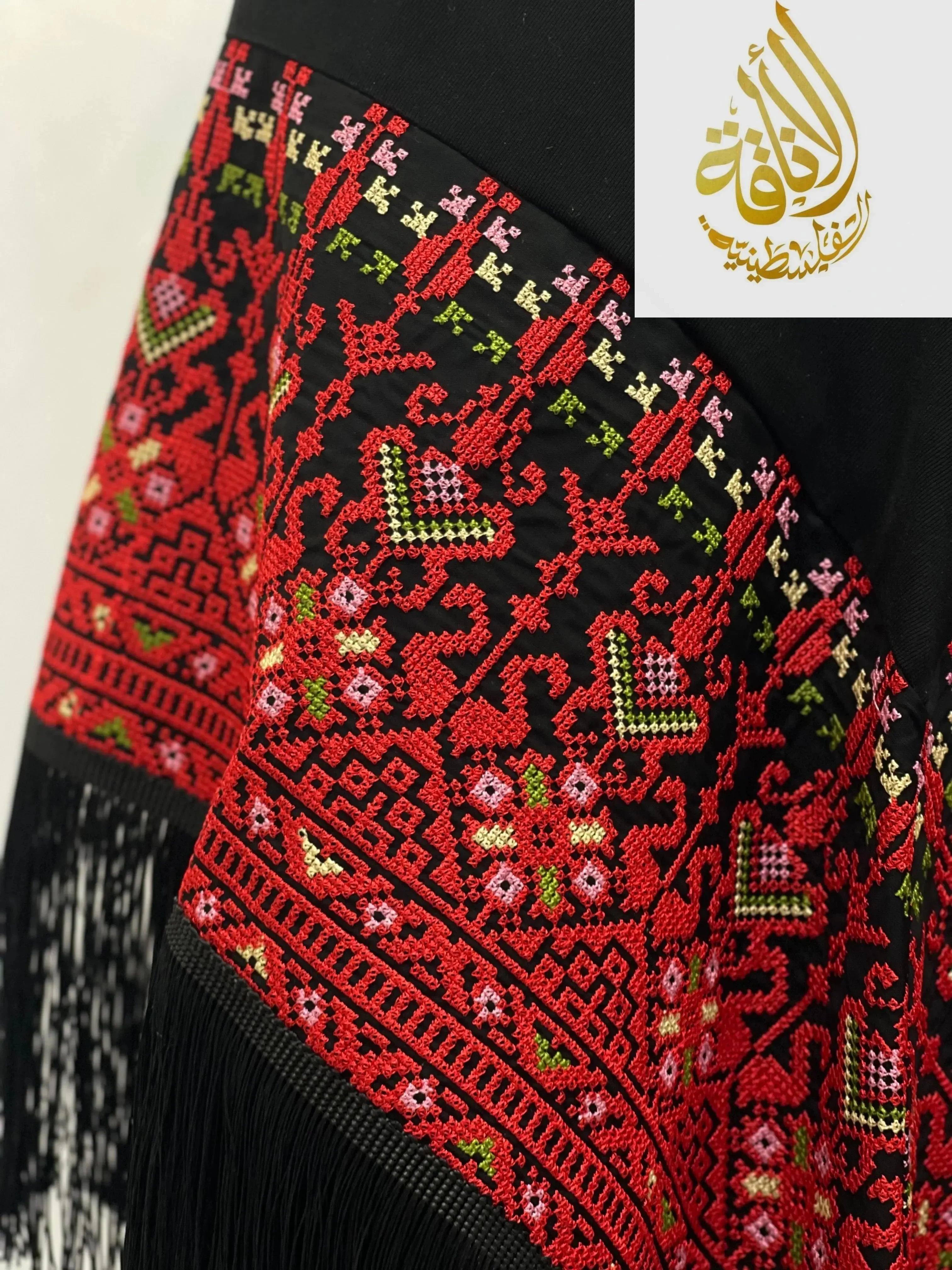 Palestinian embroidered shawl by Palestinian Elegance with red and green intricate cross stitch patterns on black fabric