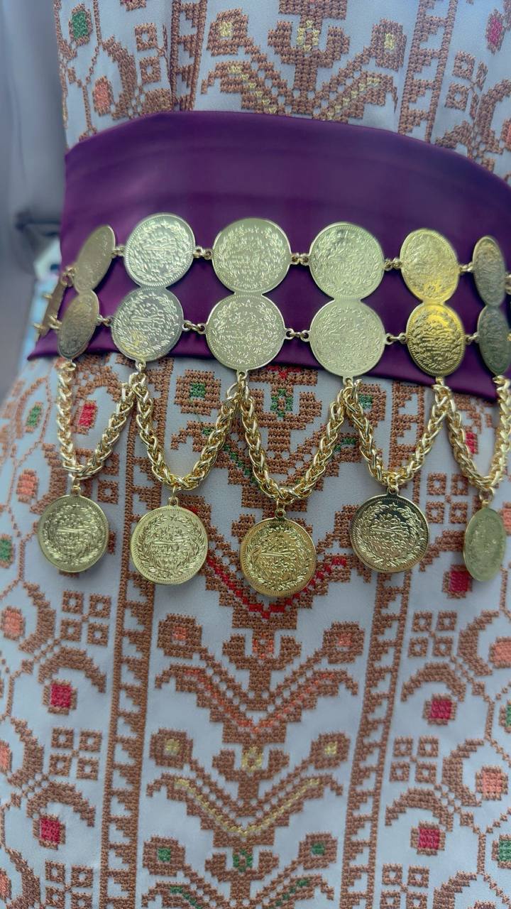 Palestinian Gold Coin-Adorned Zunnar Belt with gold coins and chains on purple fabric over traditional embroidered clothing