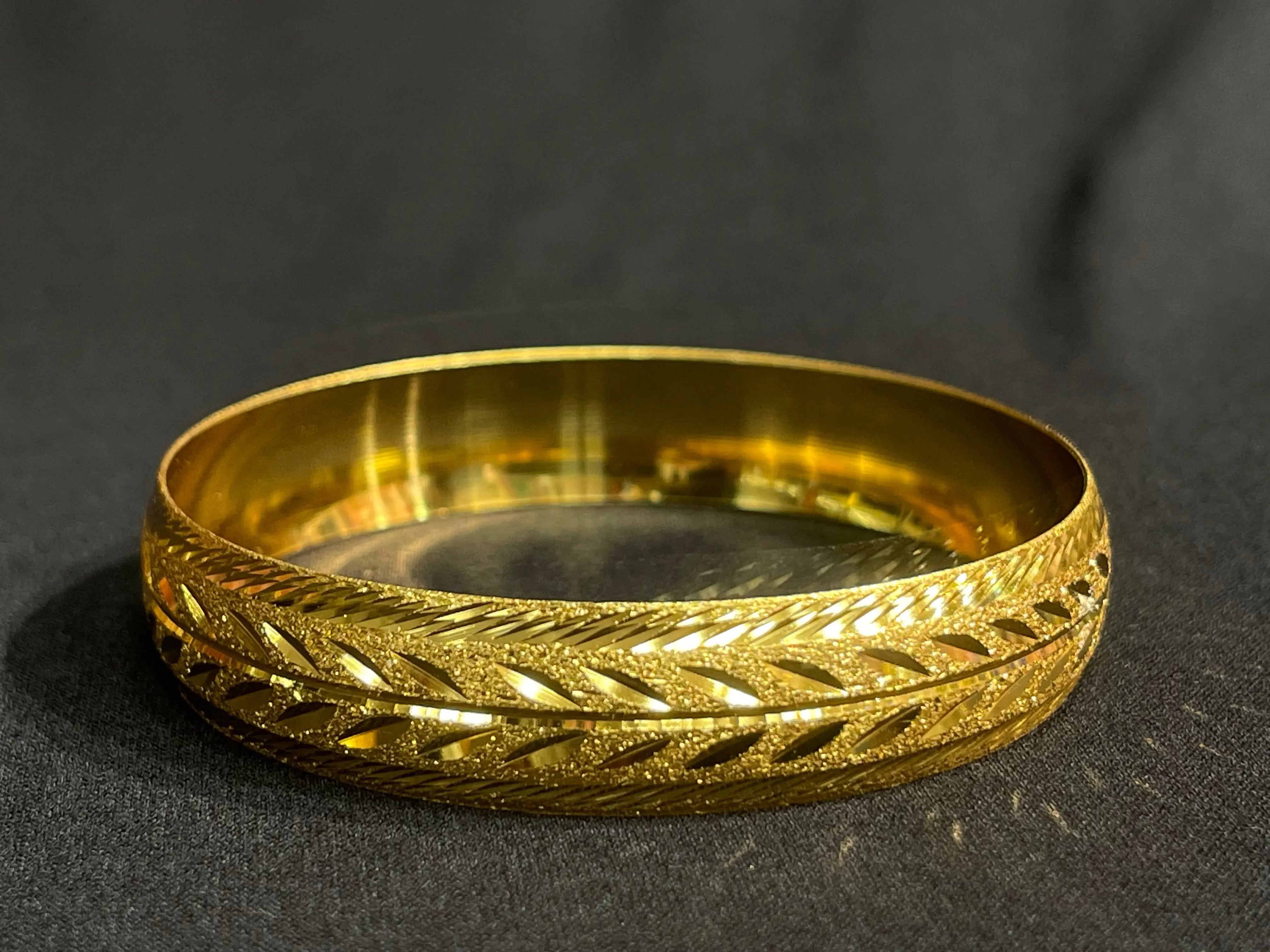 Leaf Bangles with traditional design in imitated gold by Palestinian Elegance on black background