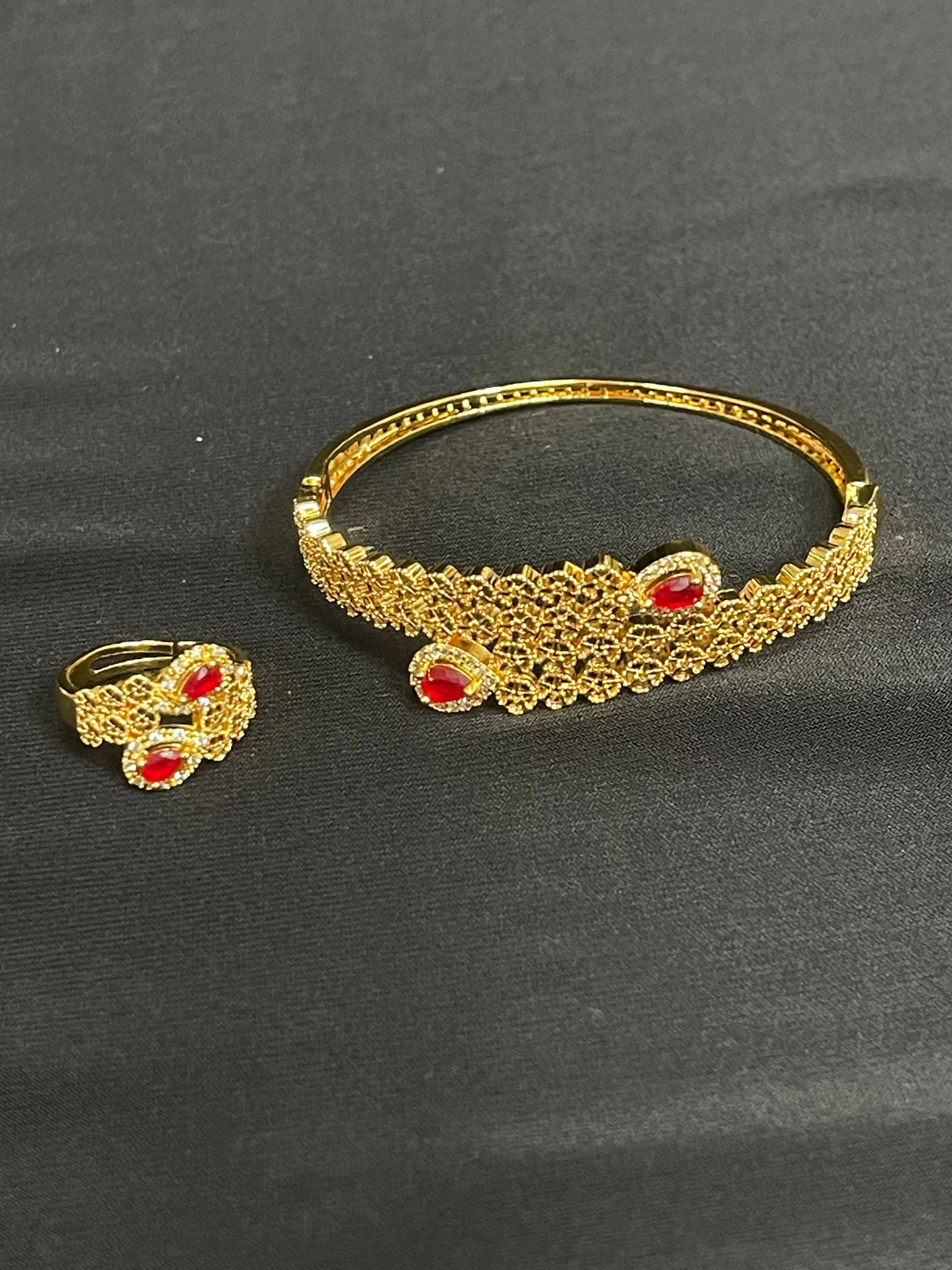 Palestinian gold jewelry set featuring intricate gold bracelet and ring with red gemstone accents