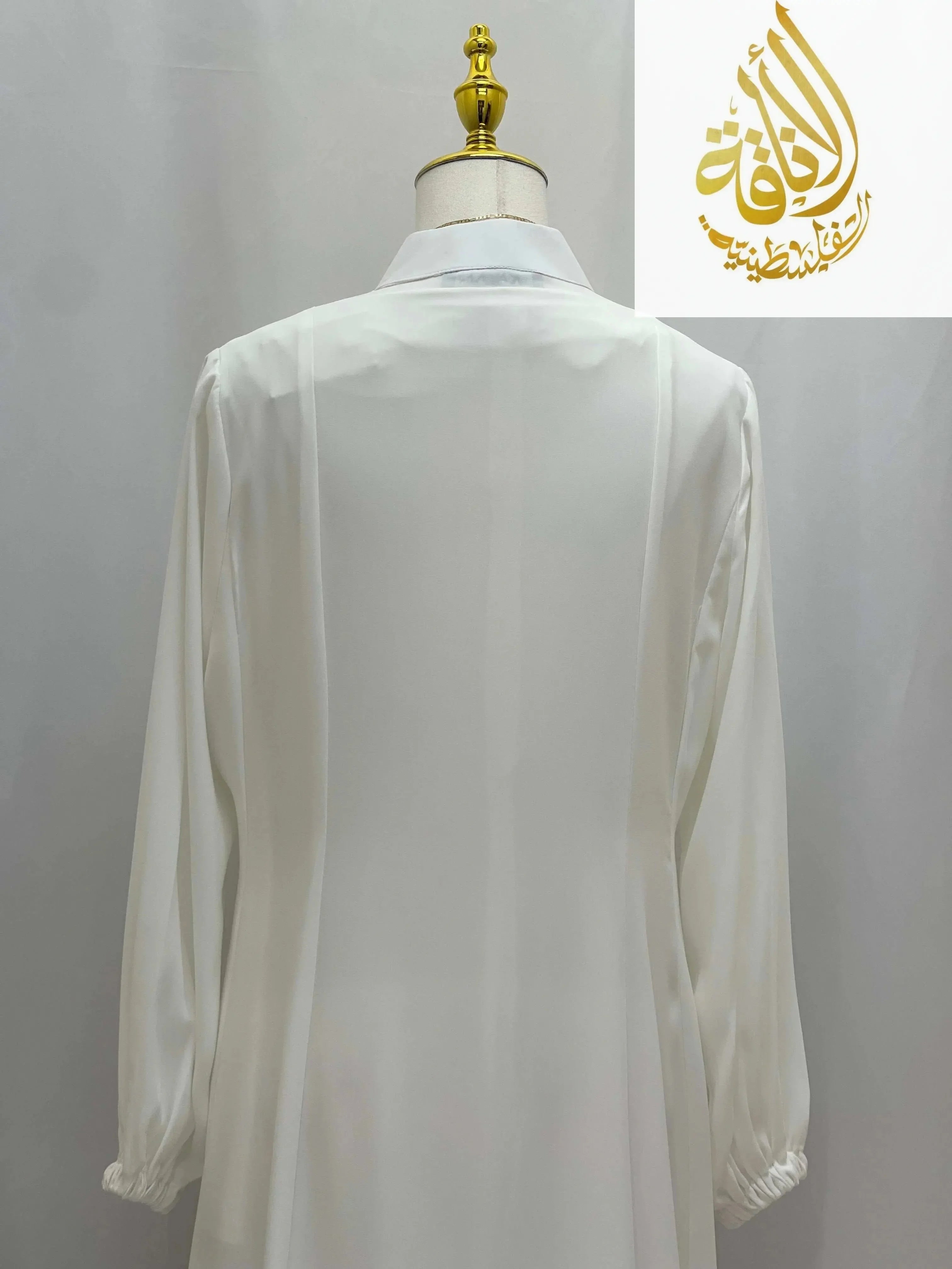 White Umra and Hajj Abaya by Palestinian Elegance displayed on mannequin with long sleeves and high collar