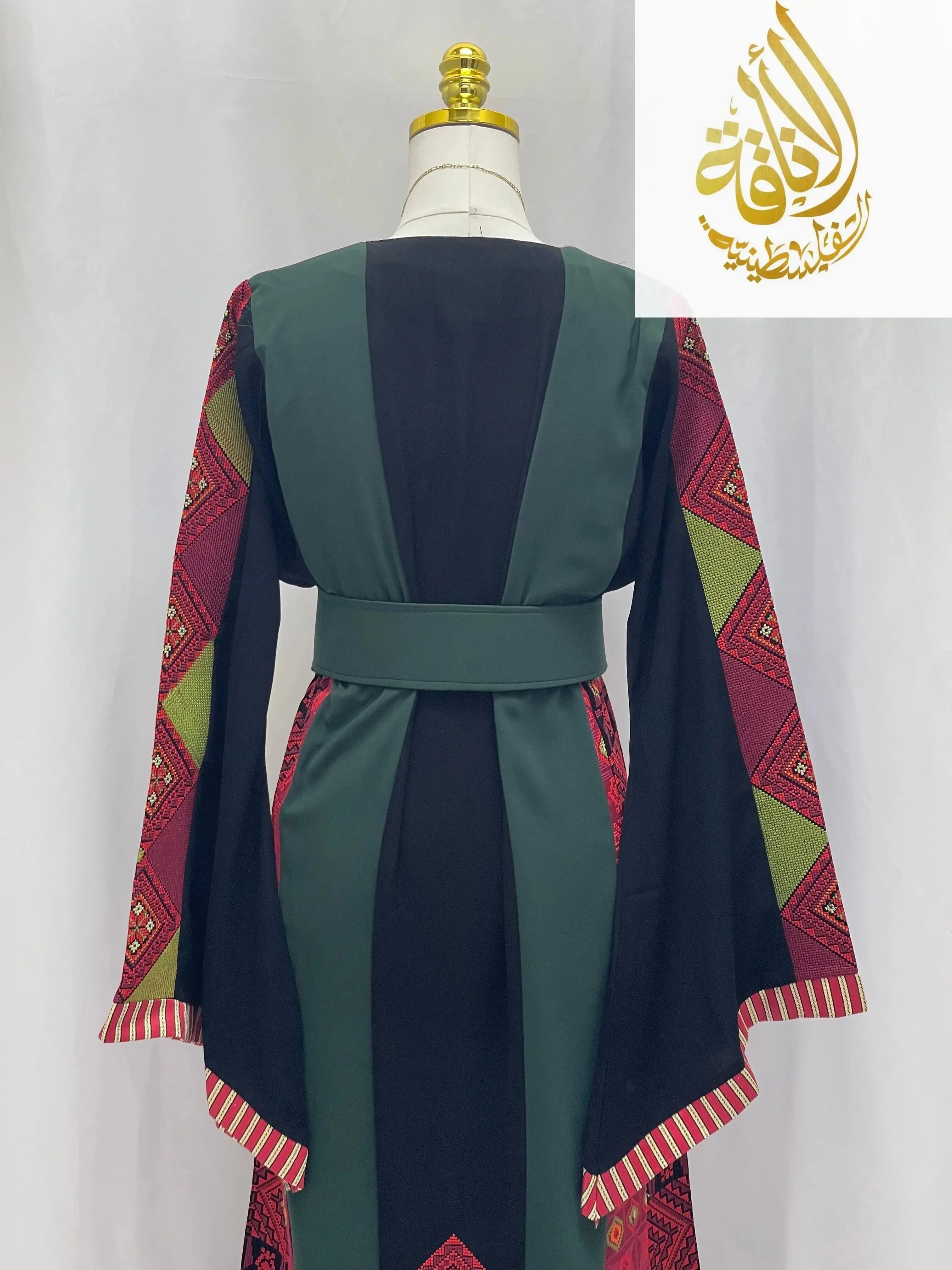 Back view of embroidered Palestinian thoub with green and black panels and red geometric sleeve patterns