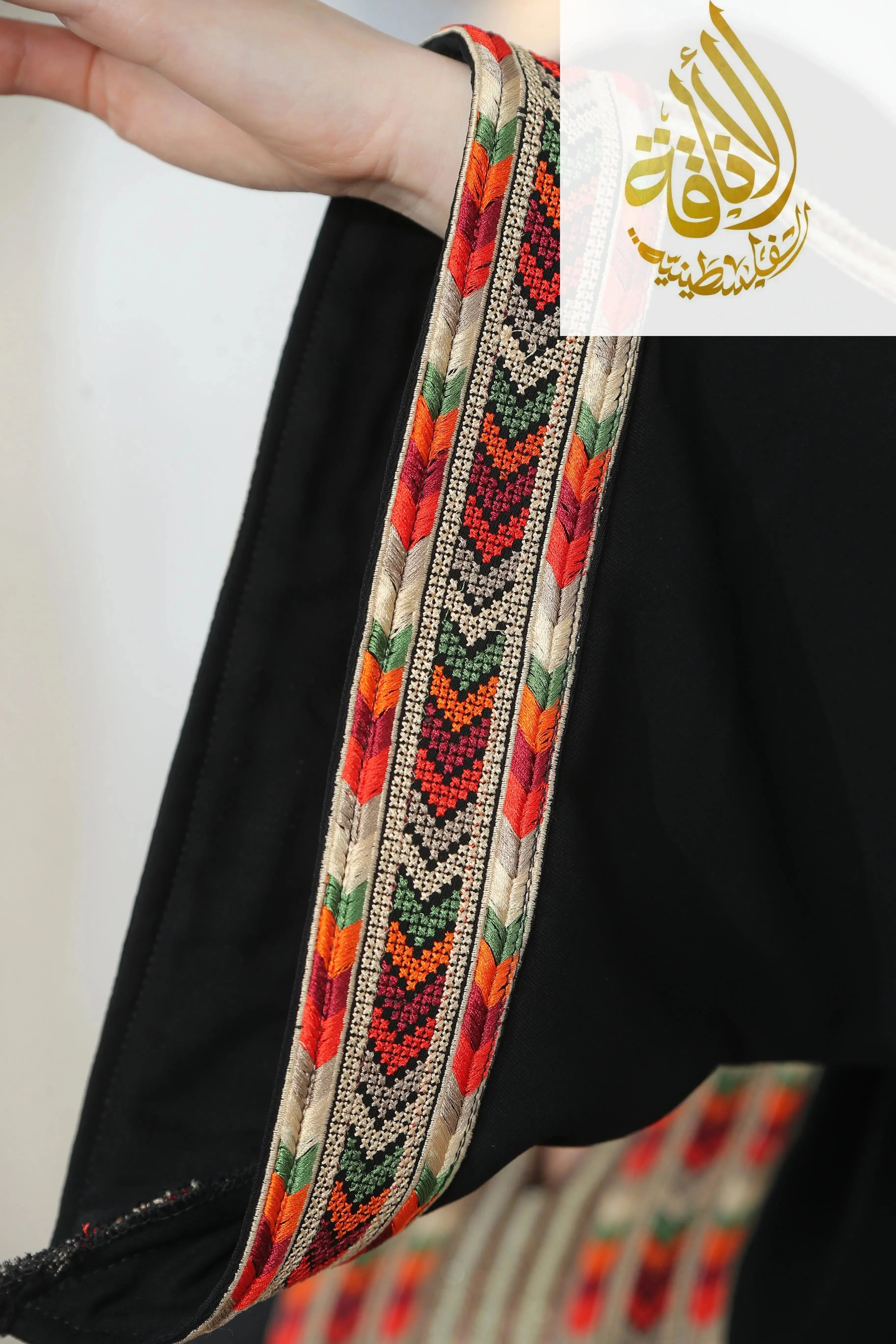 Close-up of colorful embroidered trim on Palestinian Elegance Zena Embroidered Thoub with intricate red and green patterns