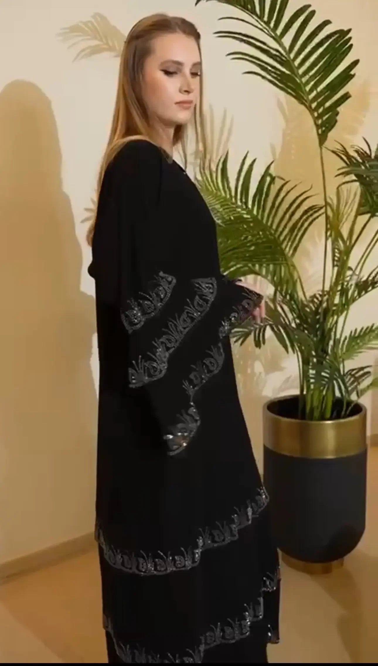 Palestinian Elegance black abaya with strass embellishments on sleeves and hem worn by woman