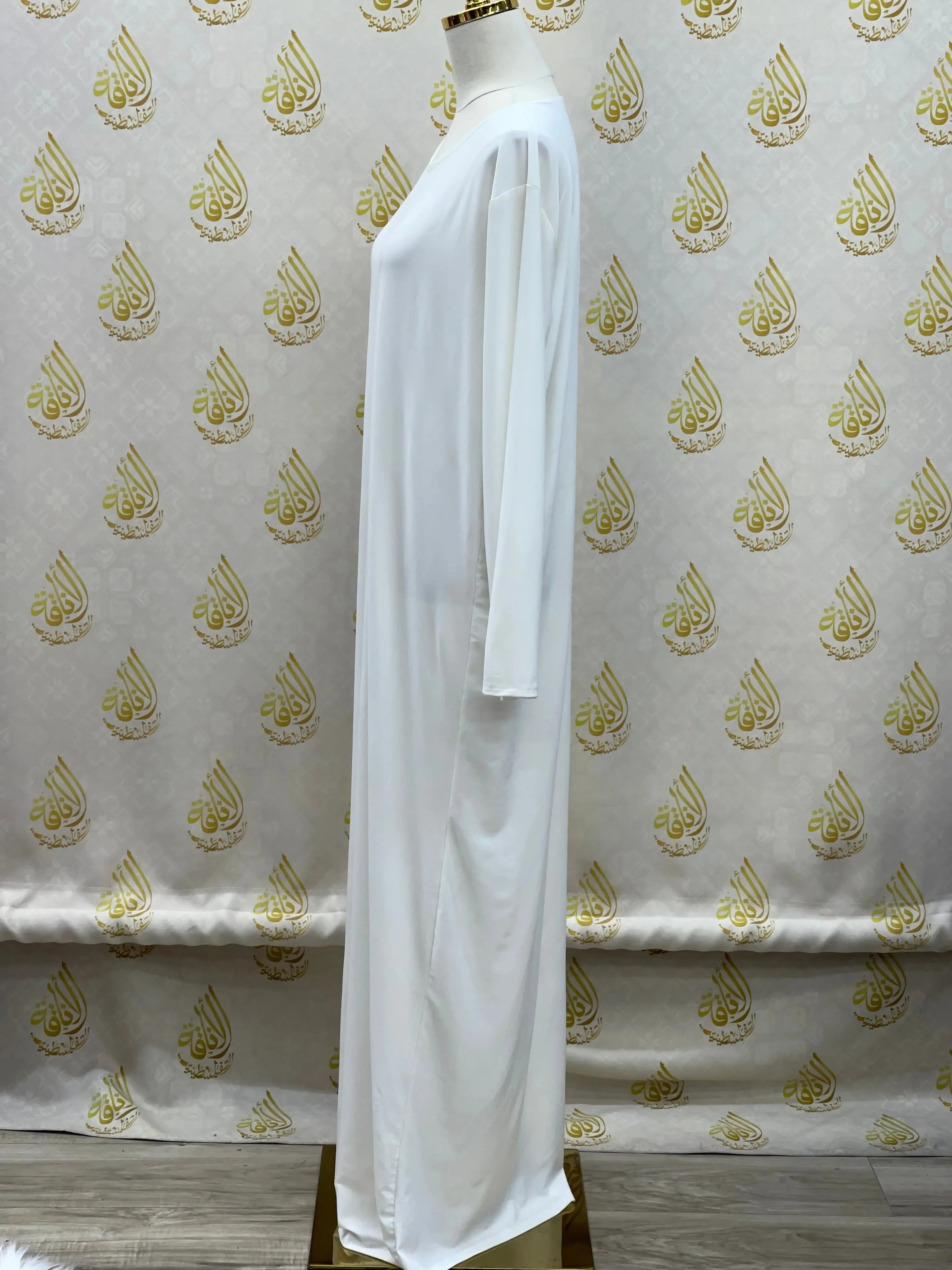 White basic solid dress with long sleeves from Palestinian Elegance displayed on a mannequin